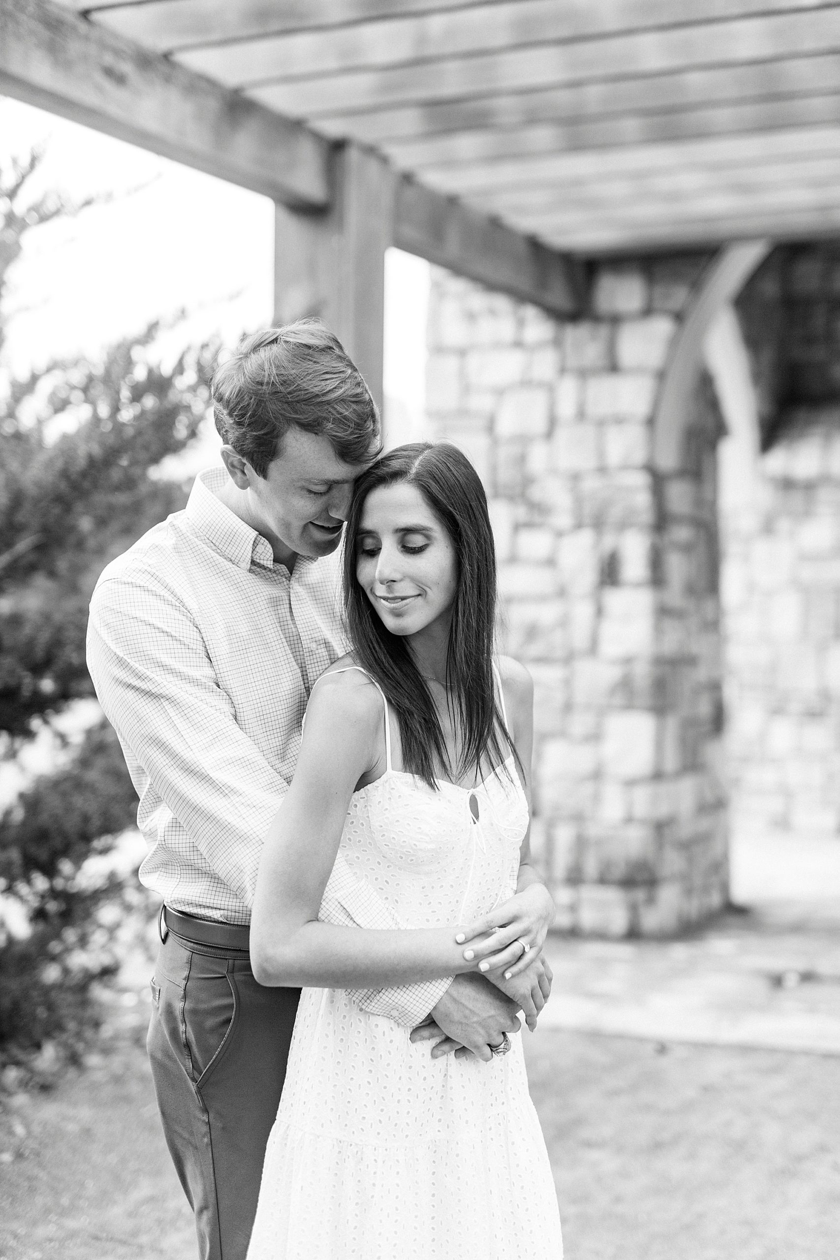 bride and groom hug under stone archway during Midtown Park engagement session