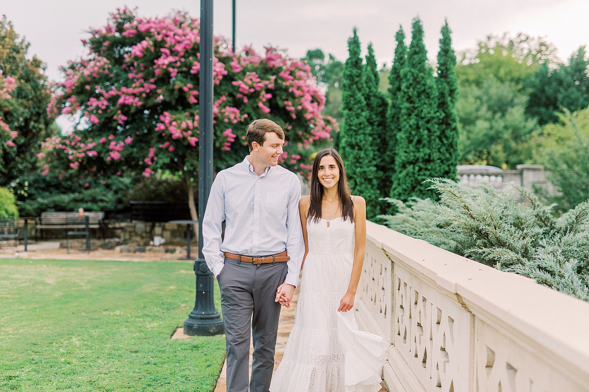 bride and groom hold hands walking along stone bridge in Midtown Park