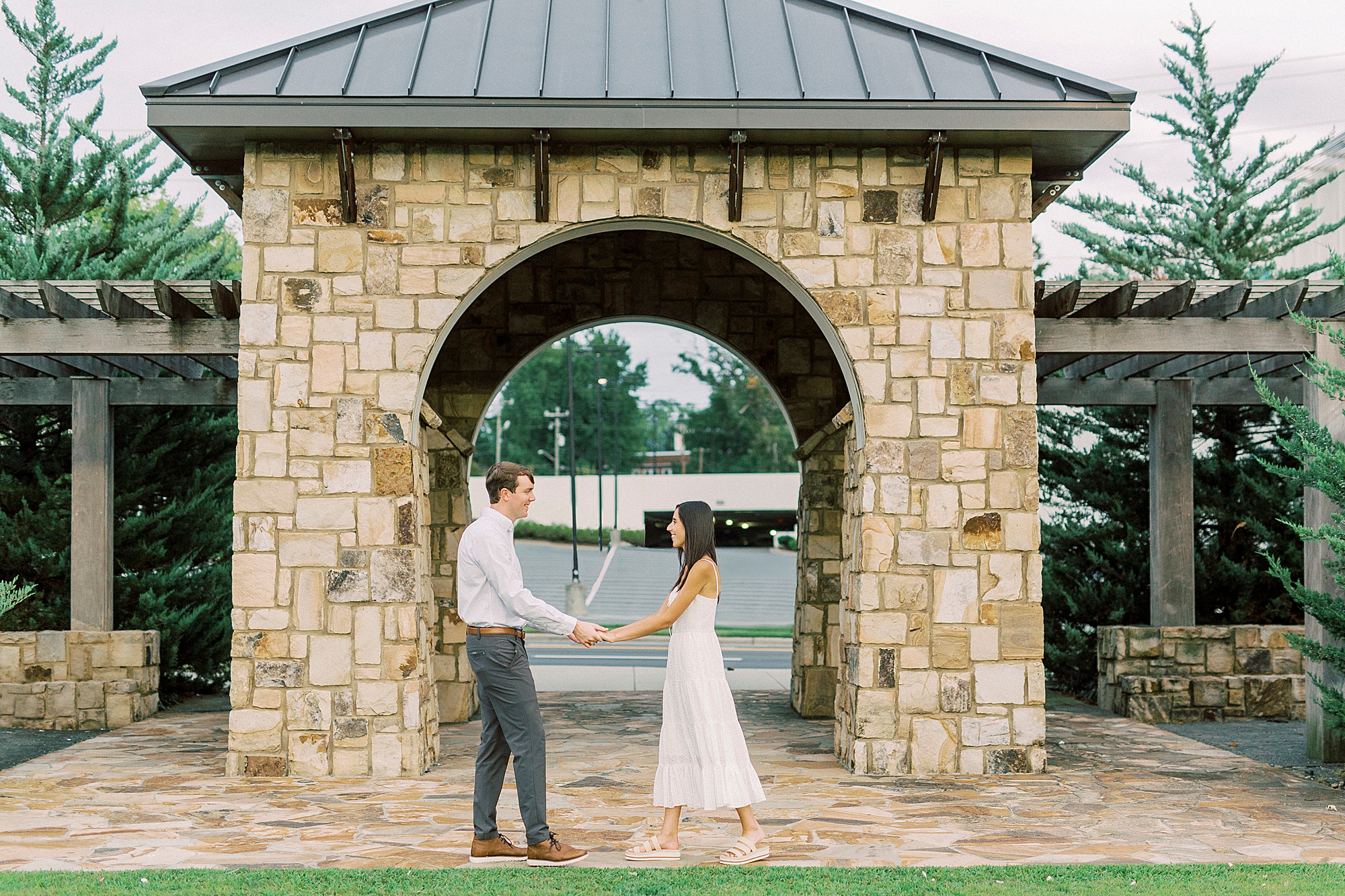 couple holds hands outside stone arbor at Midtown Park