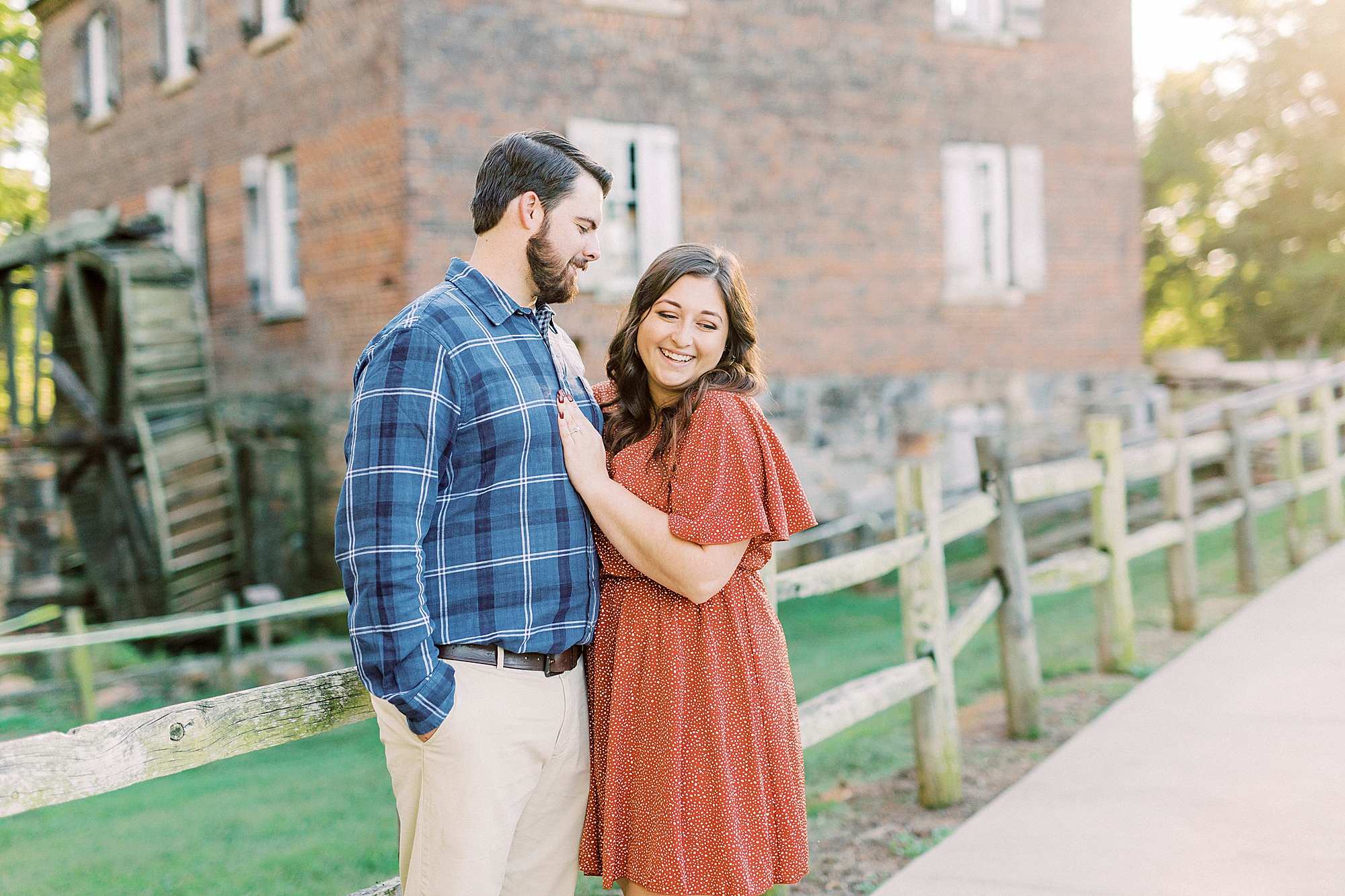 groom looks at bride in orange dress during fall engagement photos