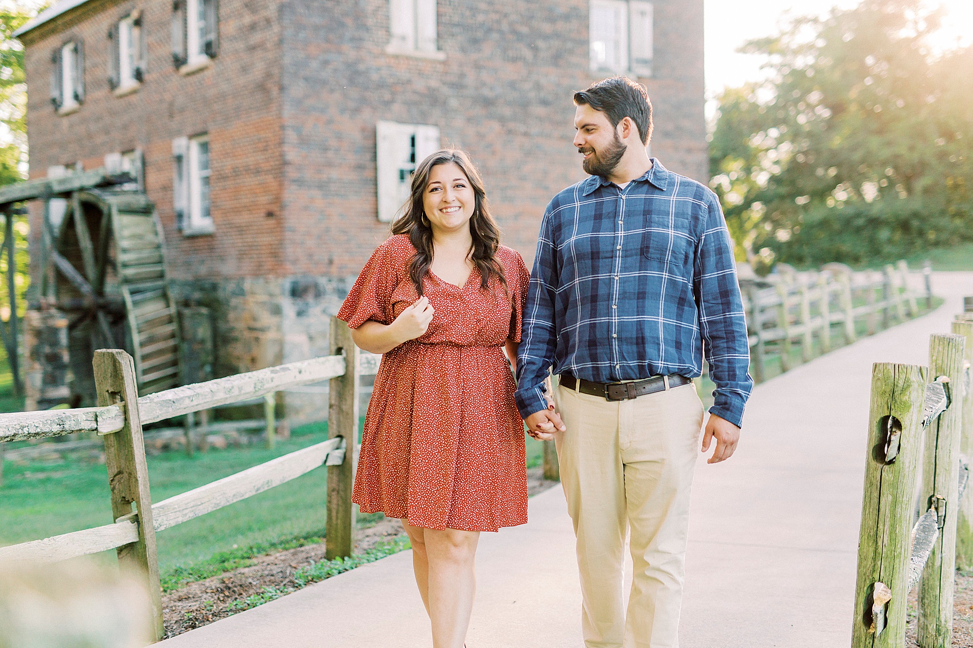 bride and groom walk by brick building at Sloan Park
