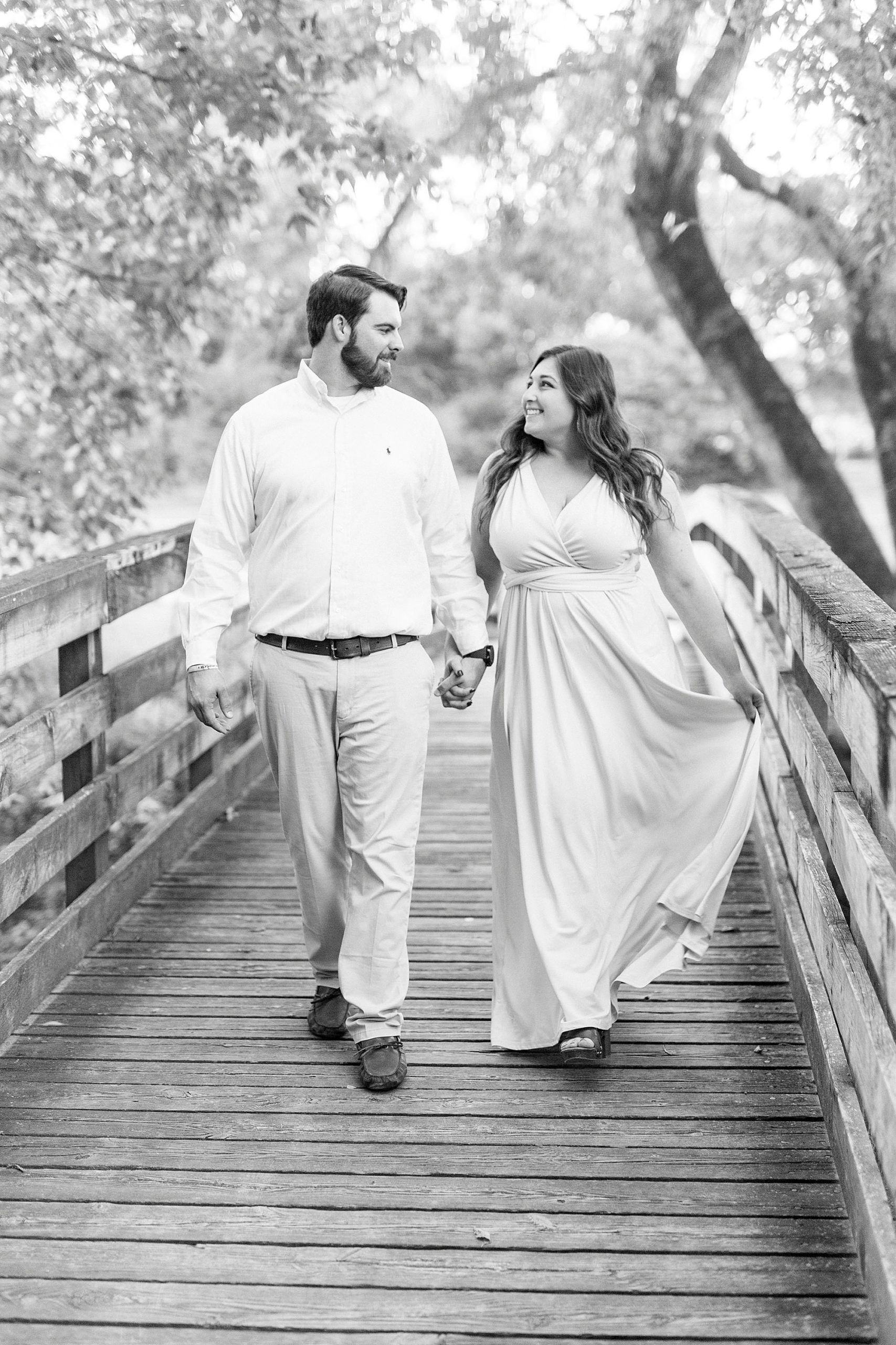 couple holds hands walking over bridge in Sloan Park