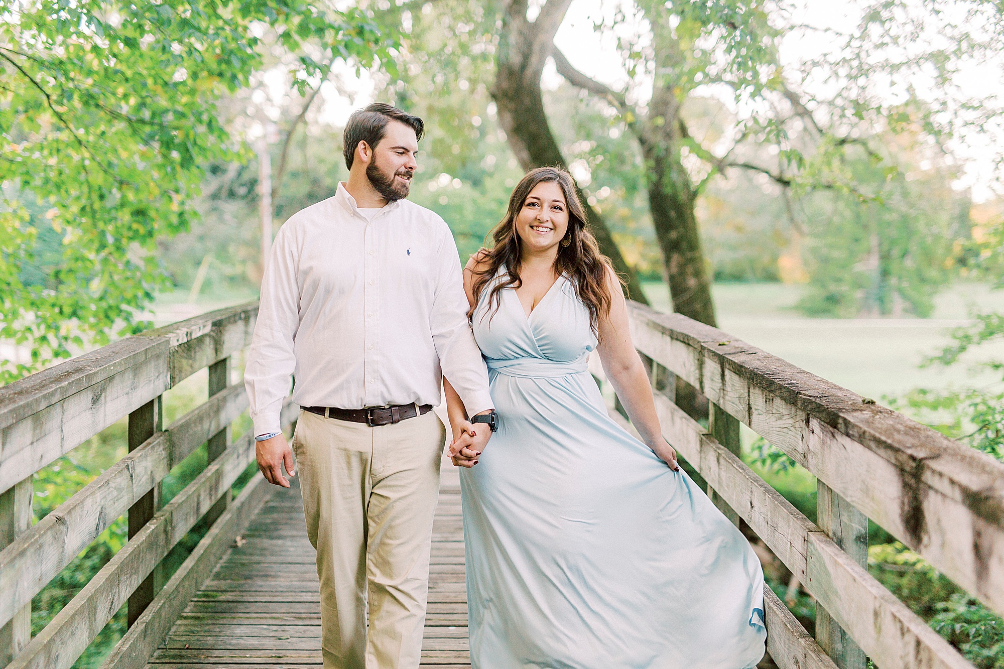 bride and groom hold hands walking over bridge during Sloan Park engagement session