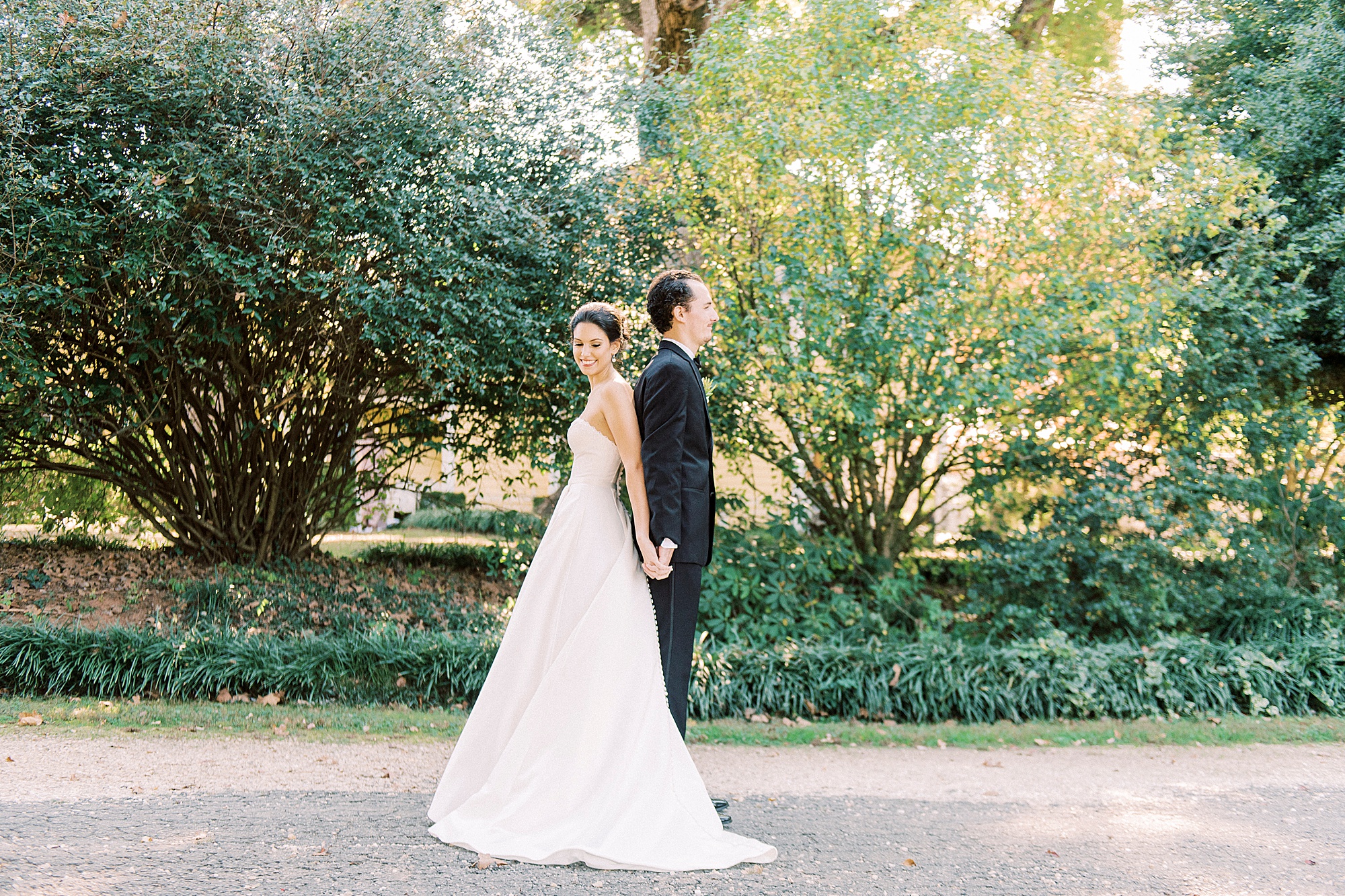 bride and groom stand back to back during first touch on wedding day