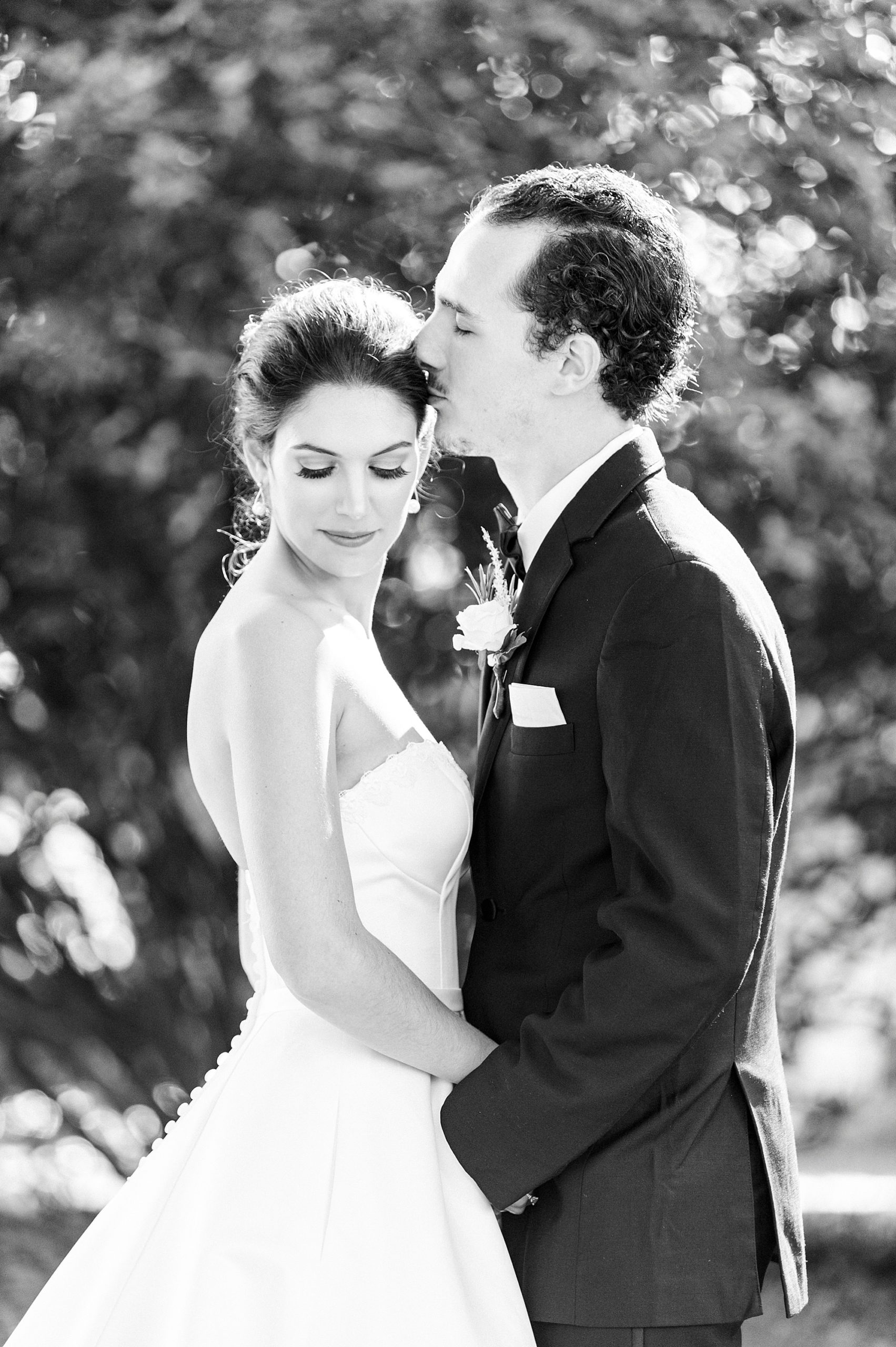groom kisses bride's forehead during NC wedding portraits