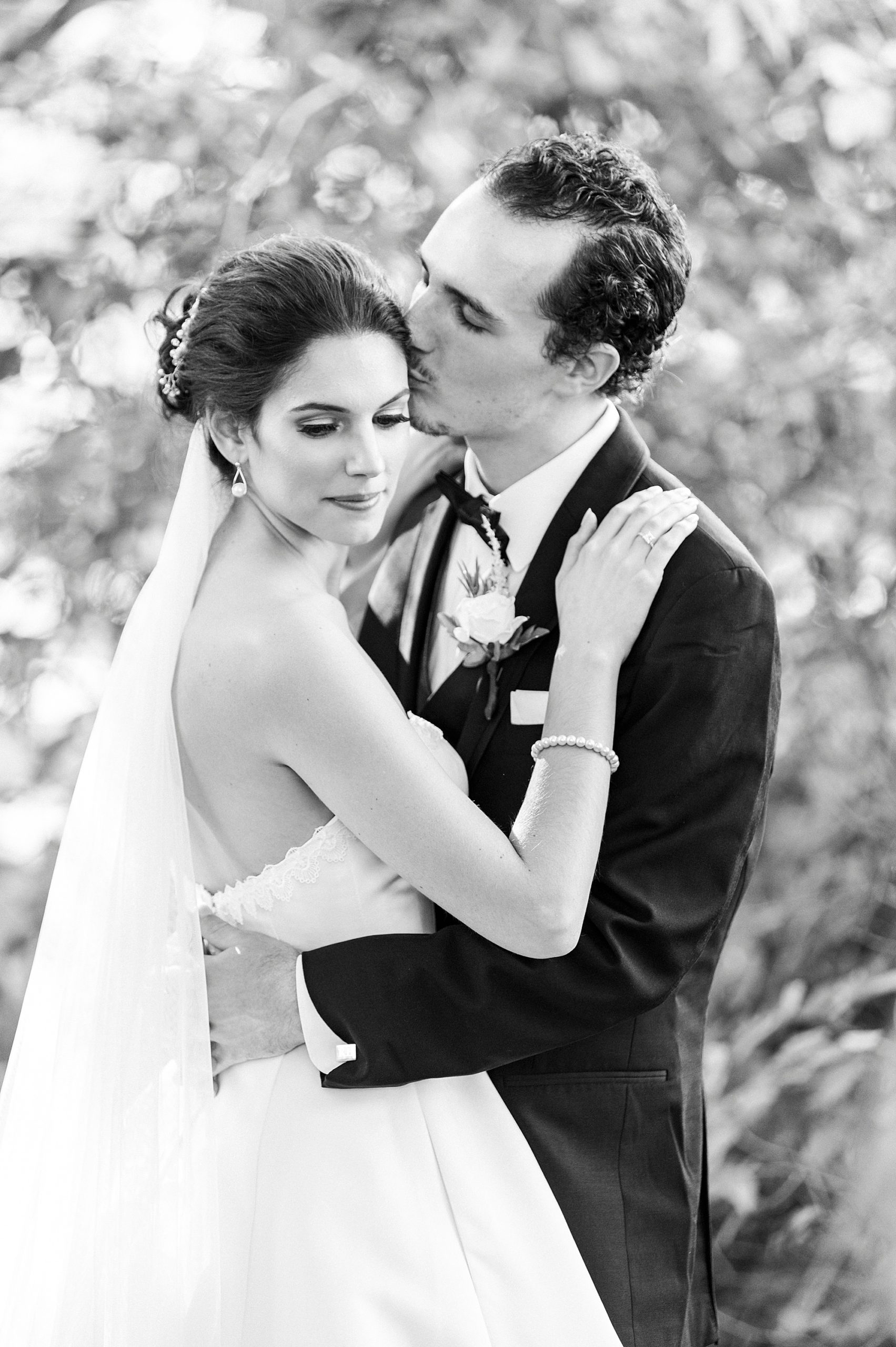 groom kisses bride's forehead during wedding portraits at 1812 Hitching Post