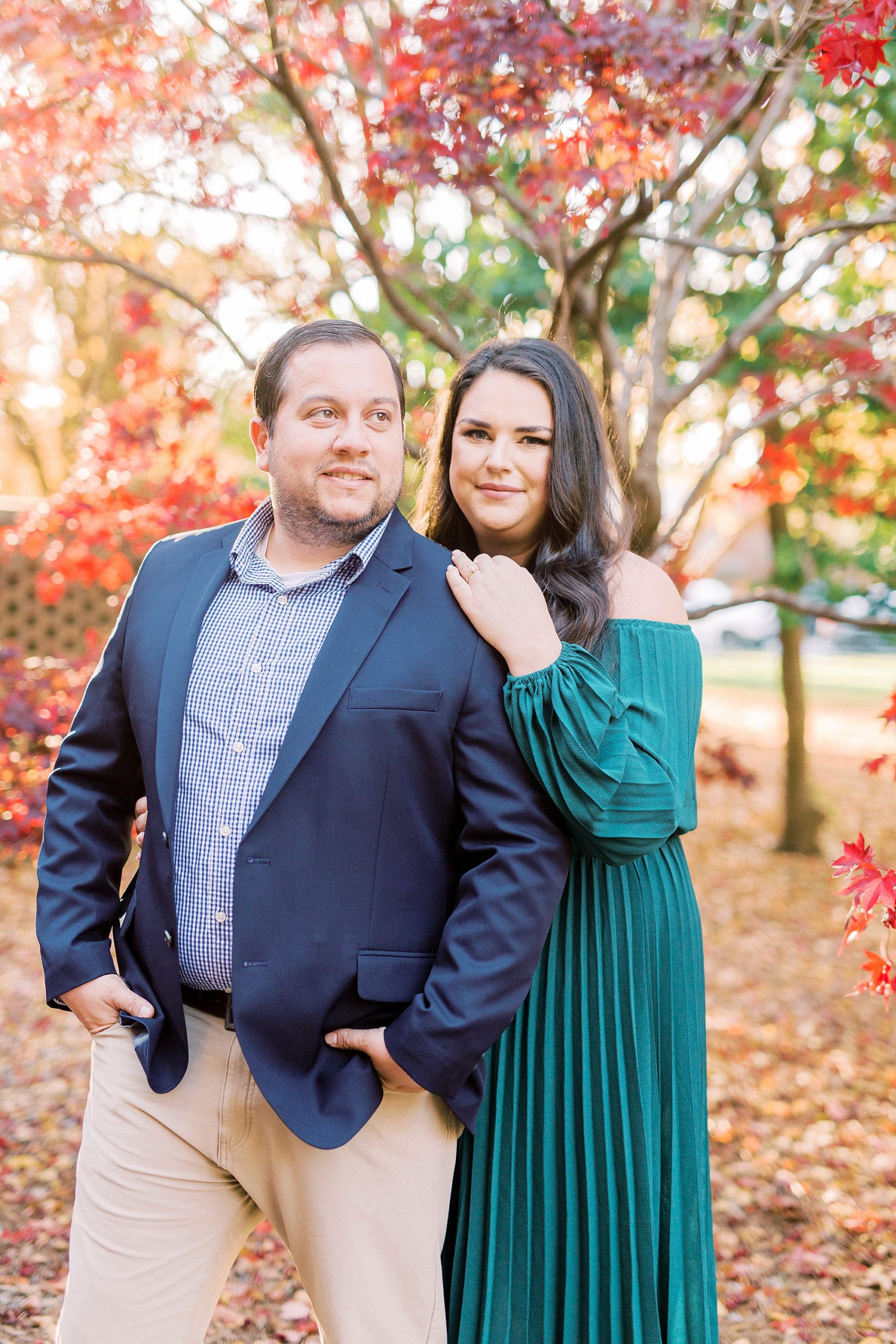 bride holds groom's shoulder during fall engagement session
