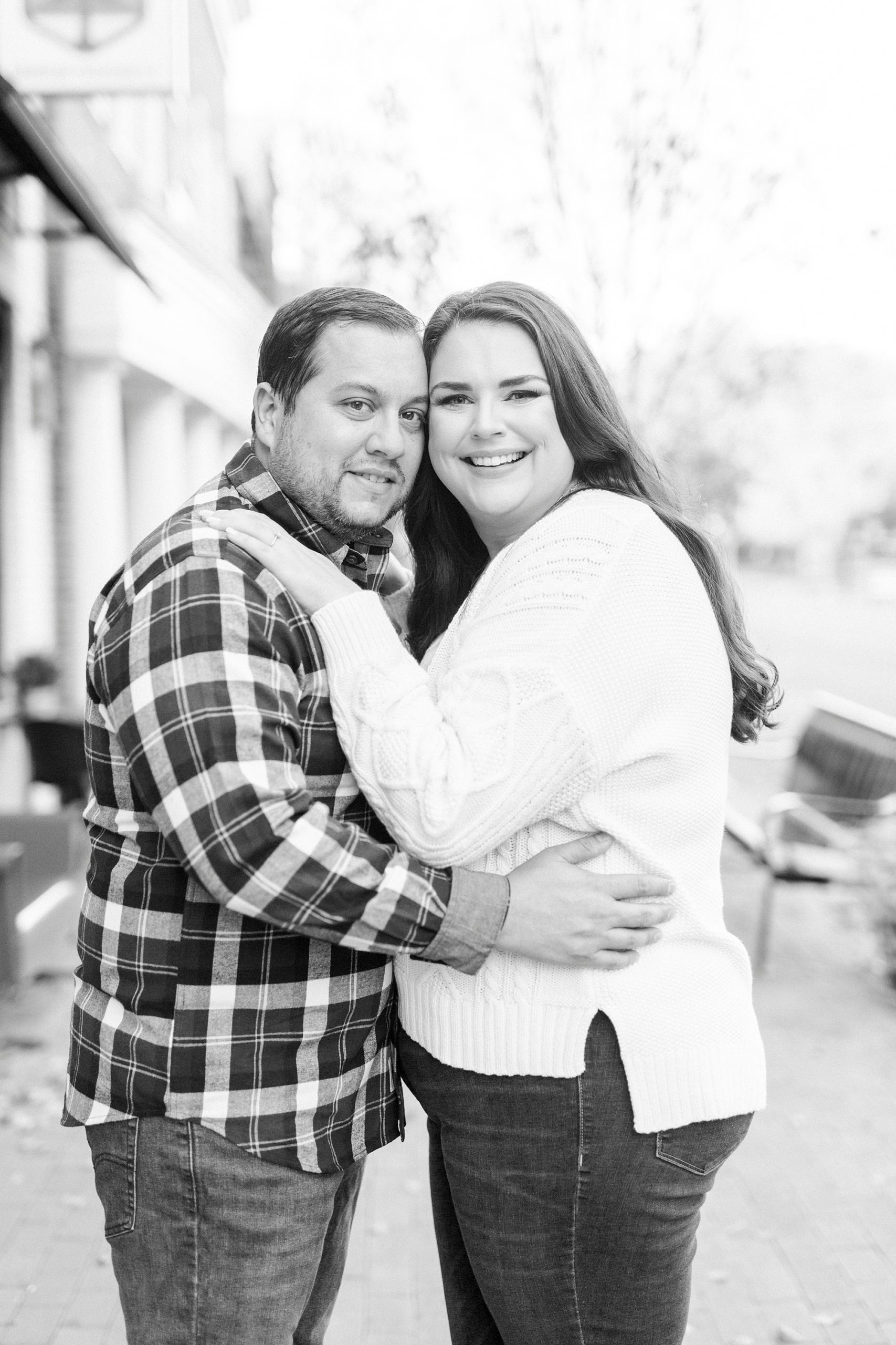 engaged couple hugs on sidewalk in Downtown Davidson