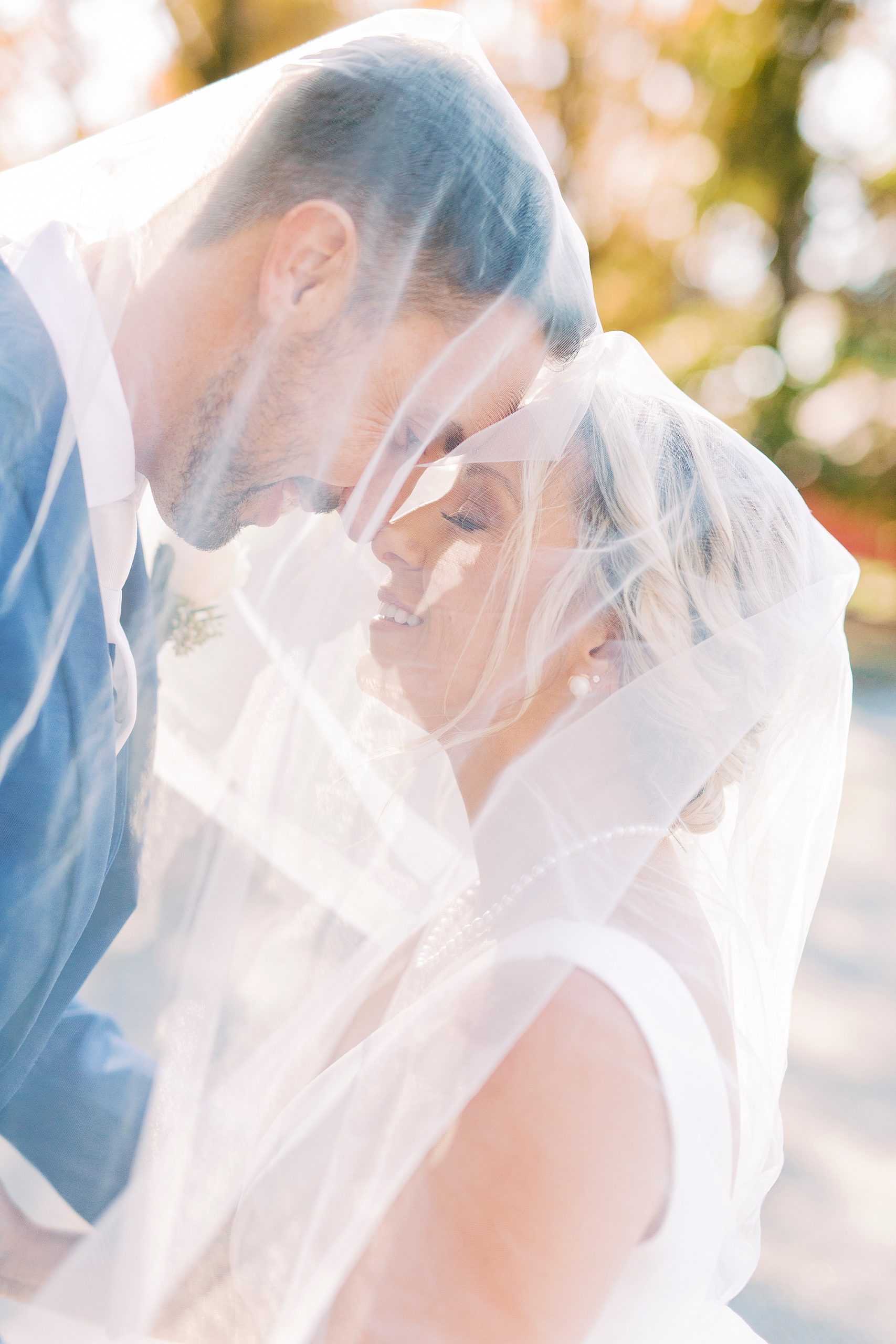 couple poses under bride's veil during portraits