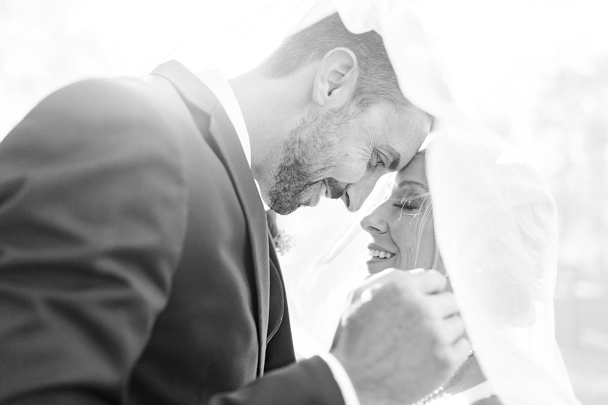 bride and groom nuzzle noses under the veil