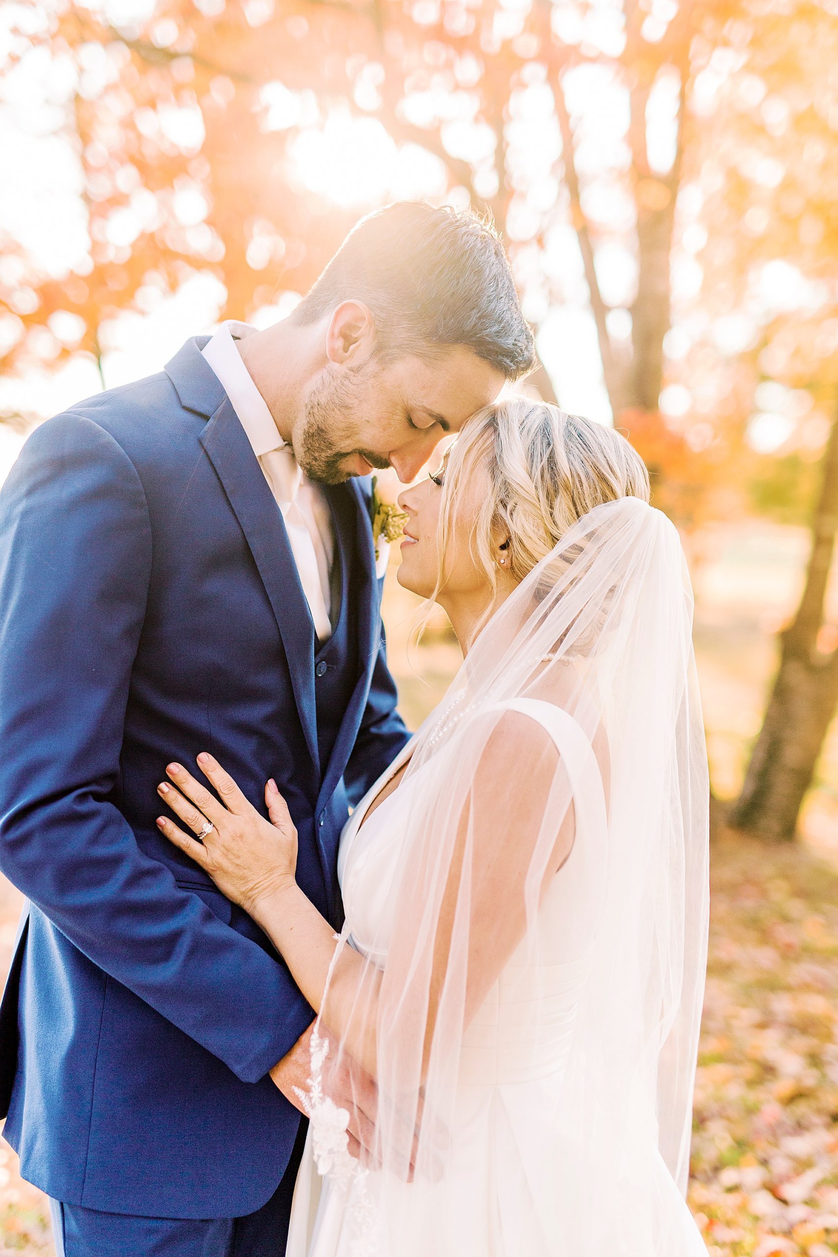 bride and groom nuzzle noses at sunset