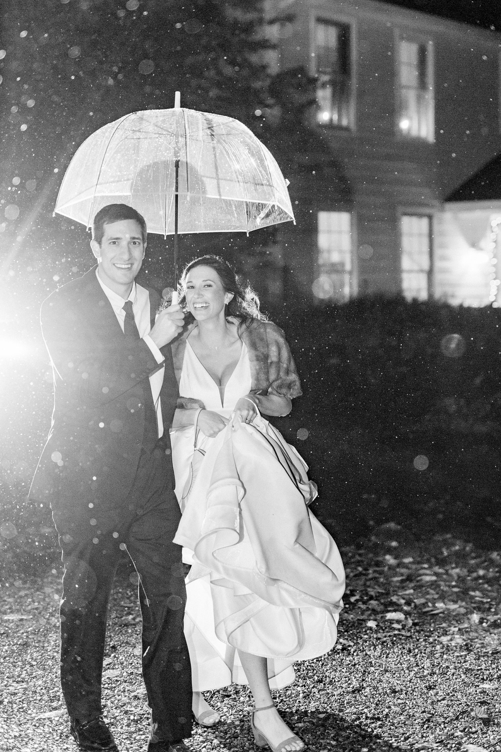 bride and groom run under umbrella during wedding portraits