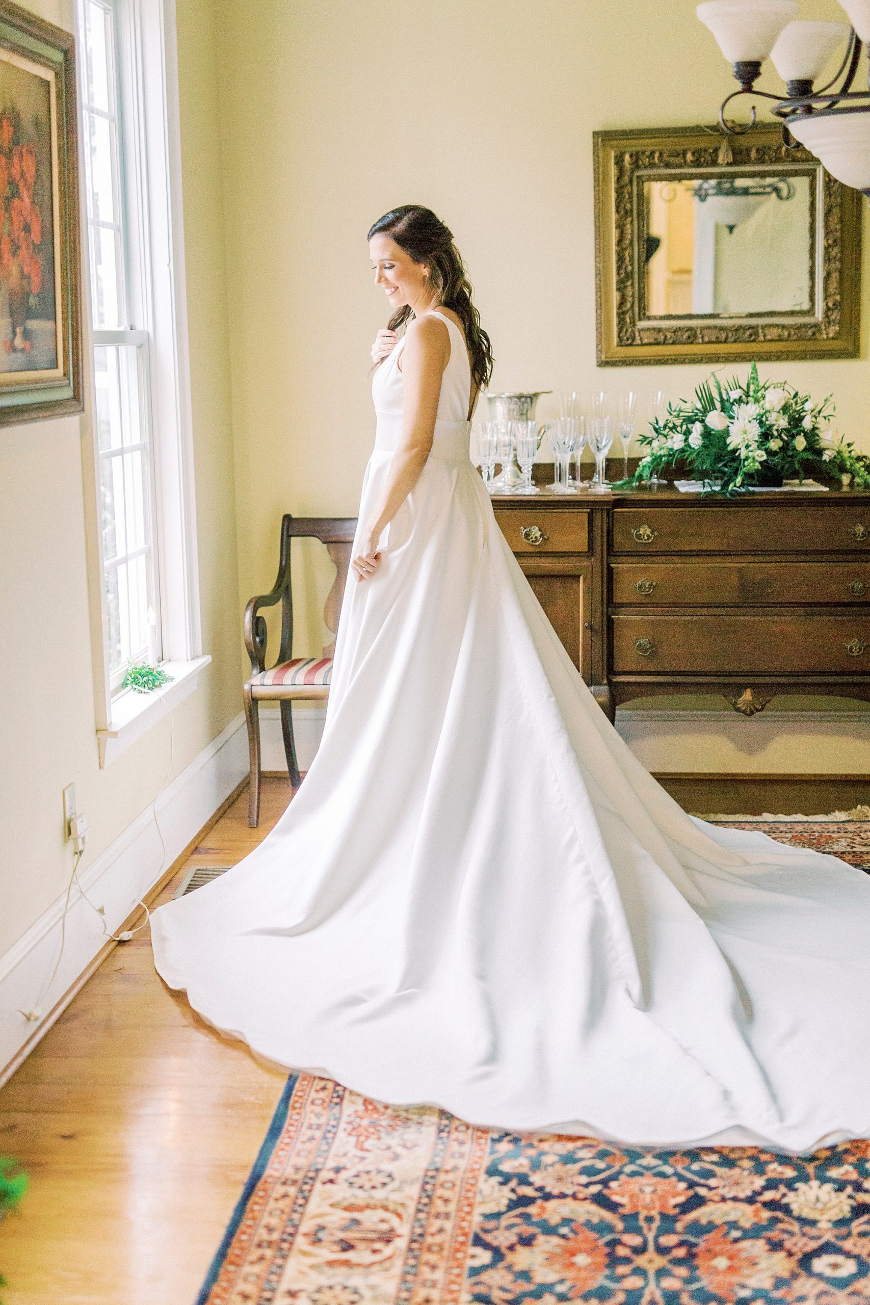 bride looks out window of family farm on morning of wedding day