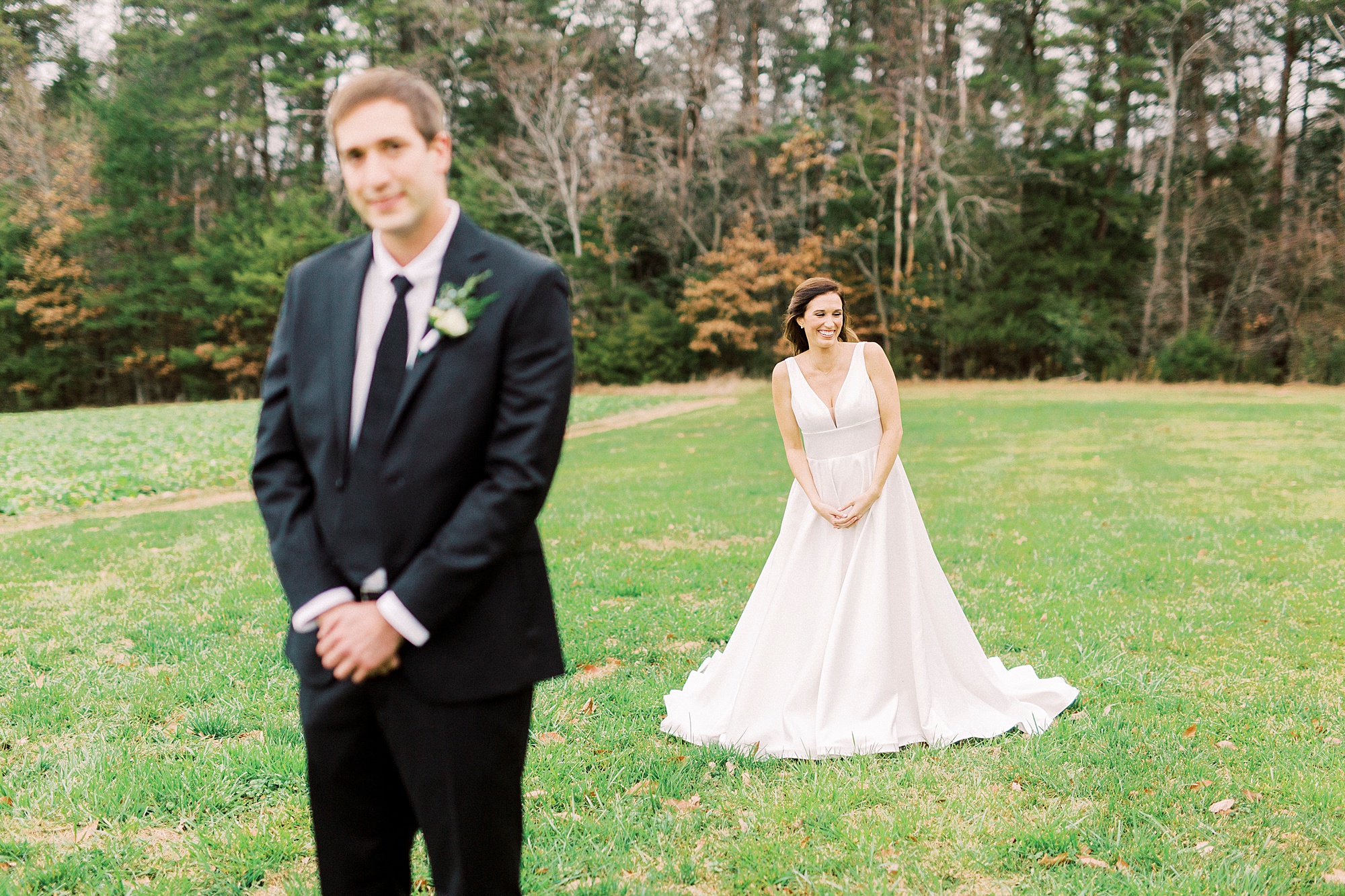 bride approaches groom for first look in field