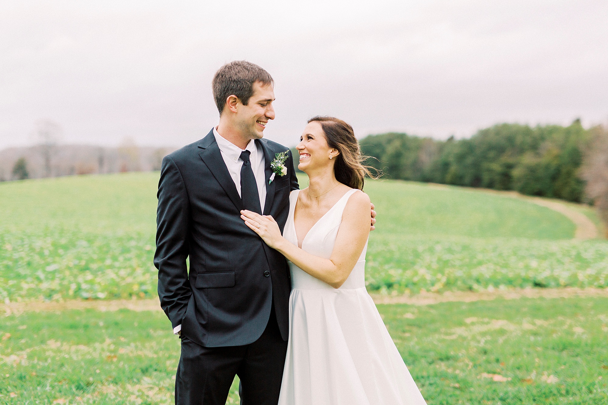 bride hugs groom looking up at him during winter wedding portraits