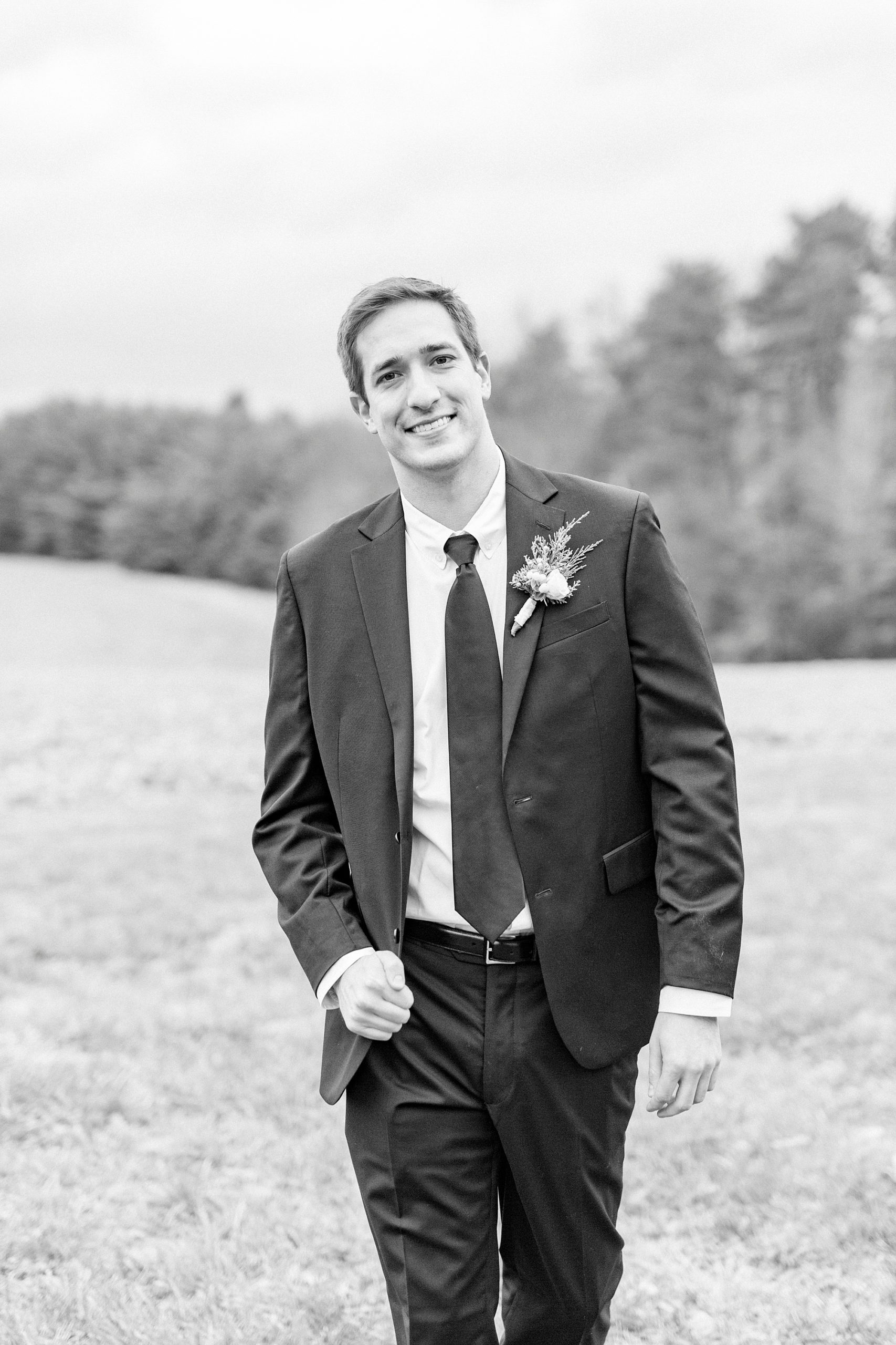 groom walks through field during portraits on wedding day