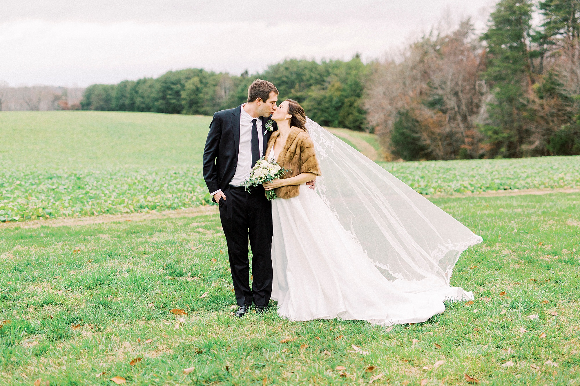newlyweds kiss while bride's veil floats behind them
