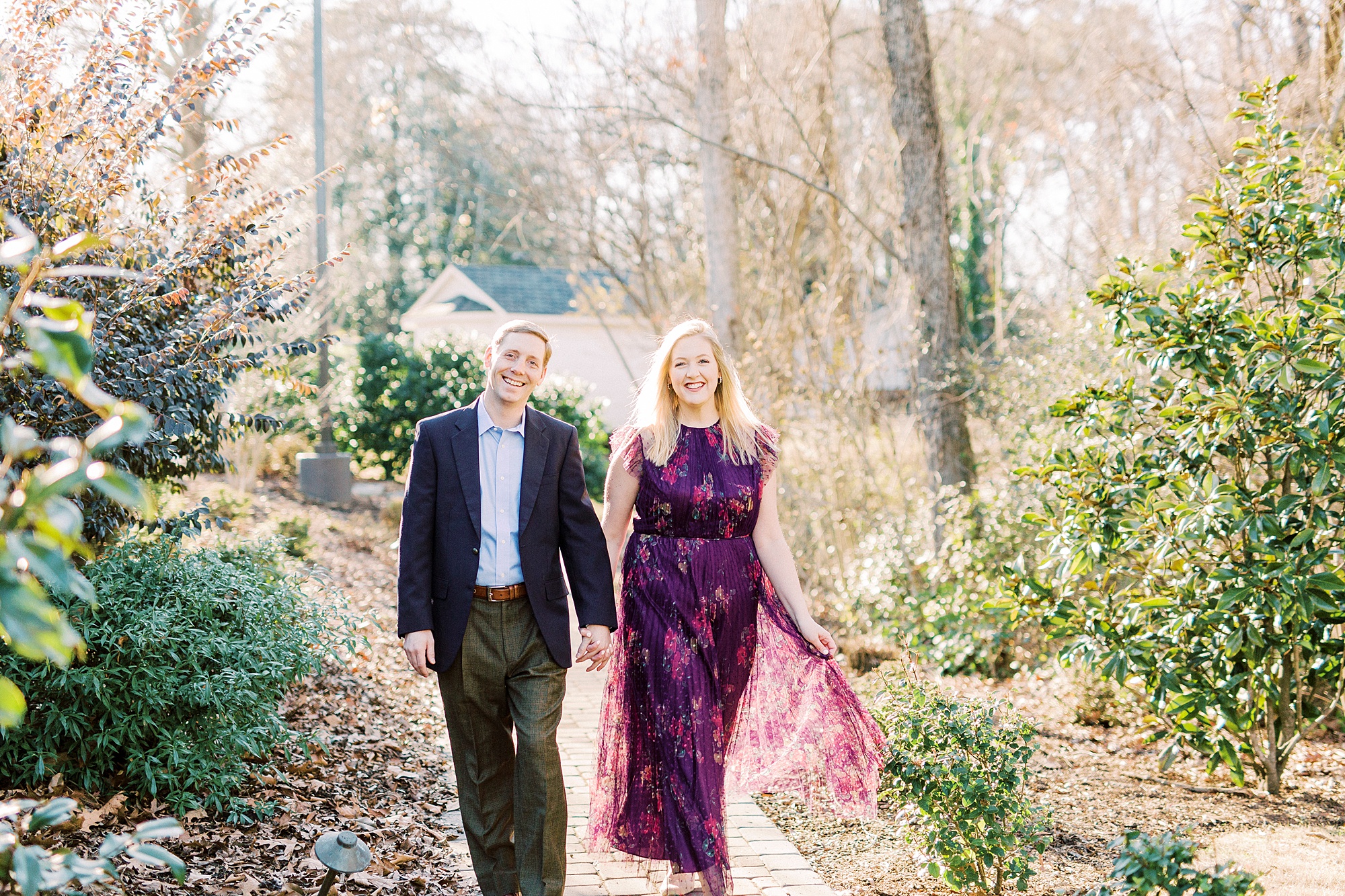 engaged couple holds hands walking through Ritchie Hill