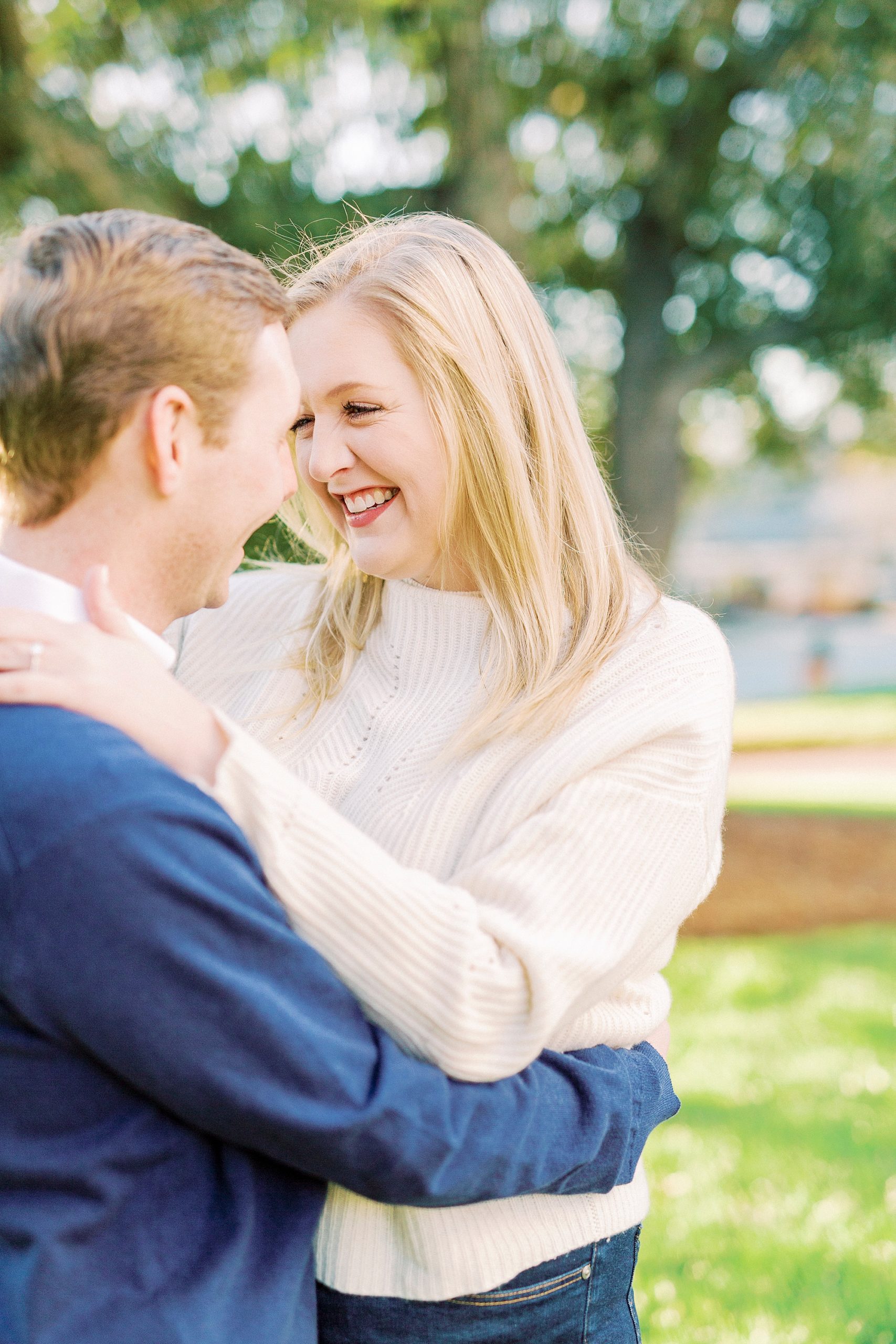 bride hugs groom during engagement photos in local park
