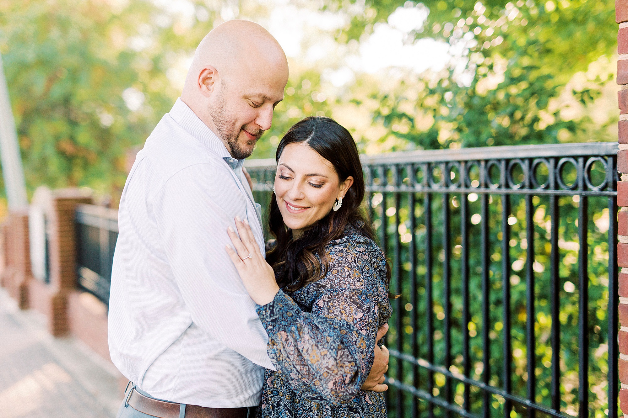bride and groom hug while bride looks at engagement ring
