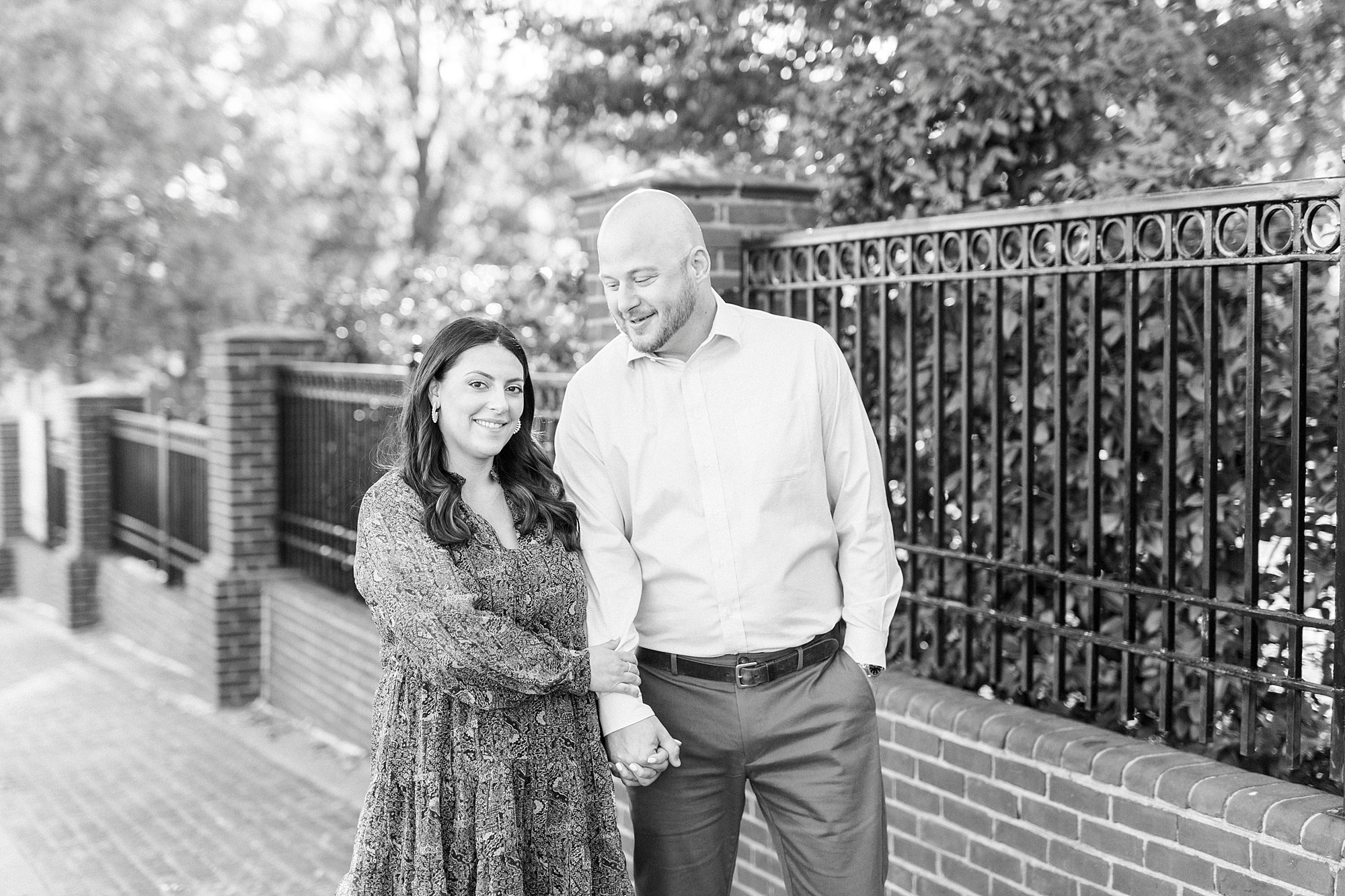 engaged couple holds hands walking down street in Downtown Matthews