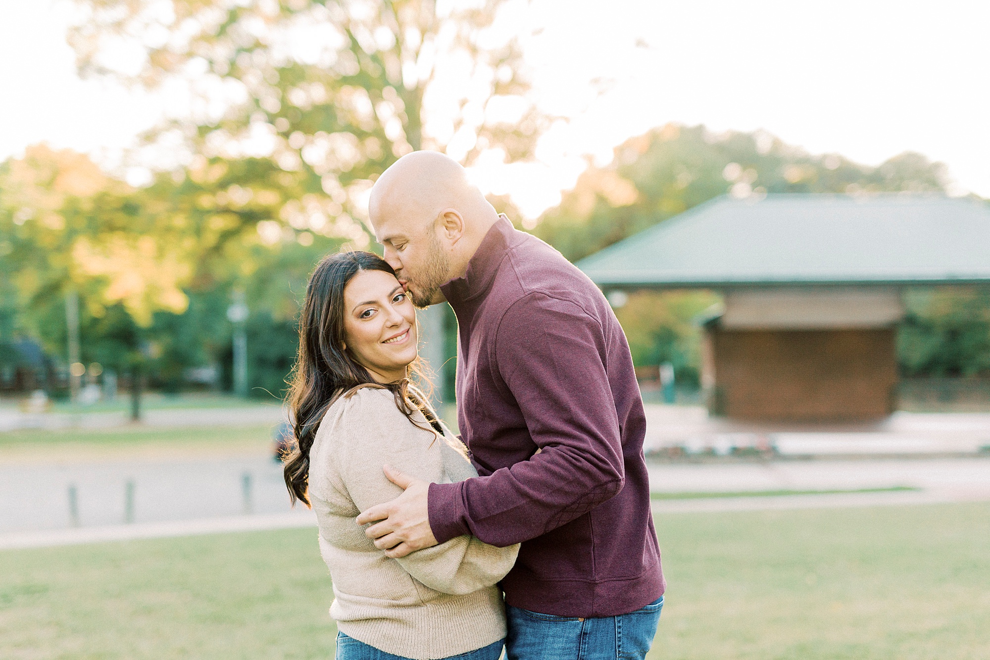 groom kisses bride's forehead during sunset Downtown Matthews engagement session