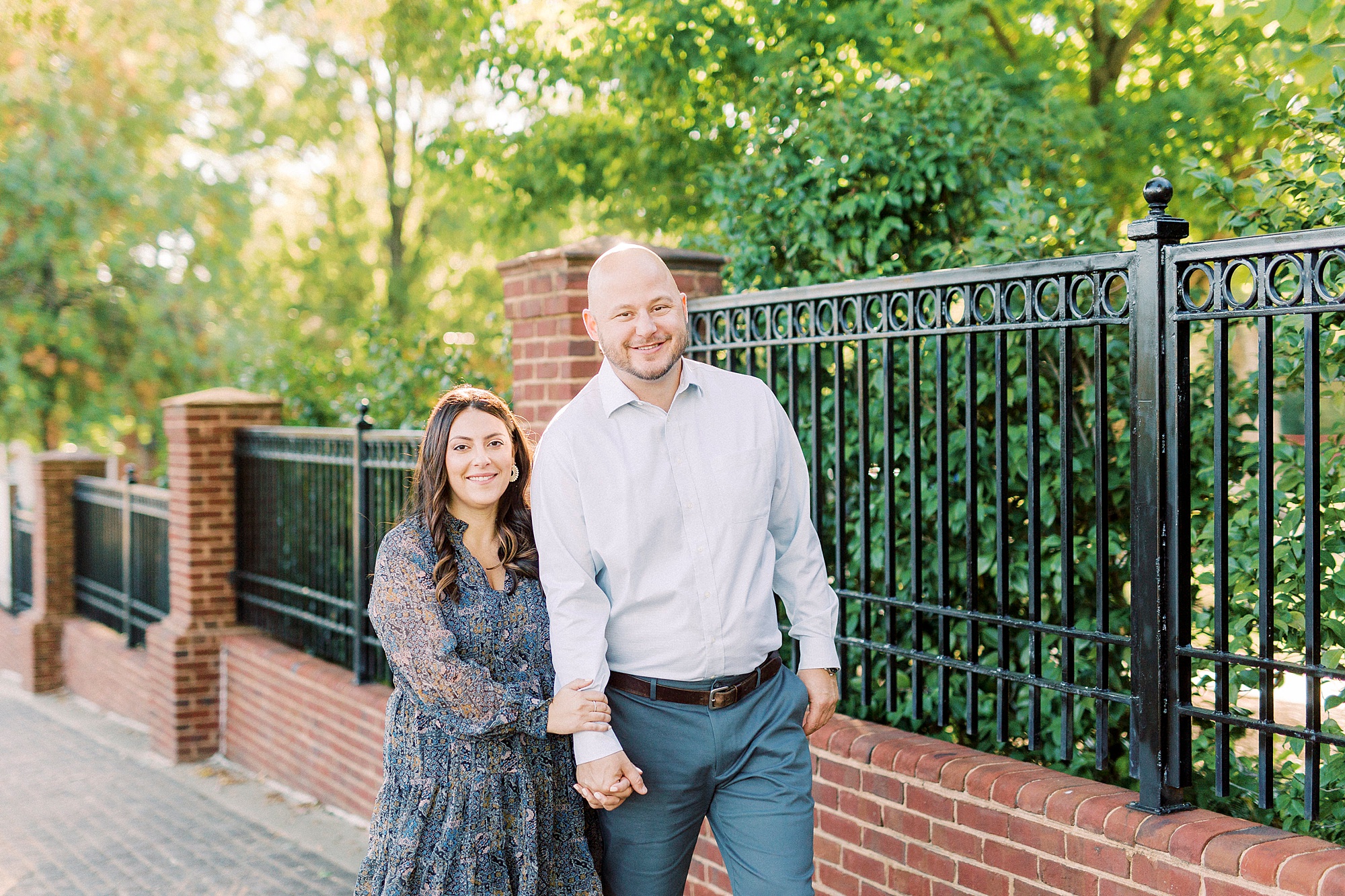 bride and groom holds hands walking down sidewalk in Downtown Matthews