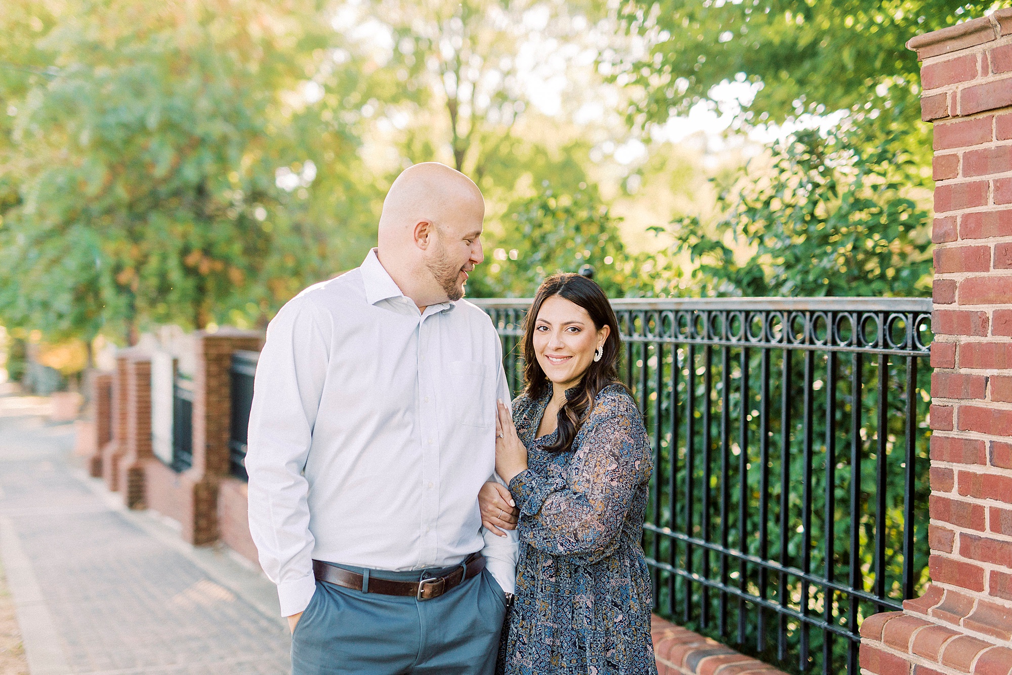 bride and groom pose by wrought iron fence in Downtown Matthews