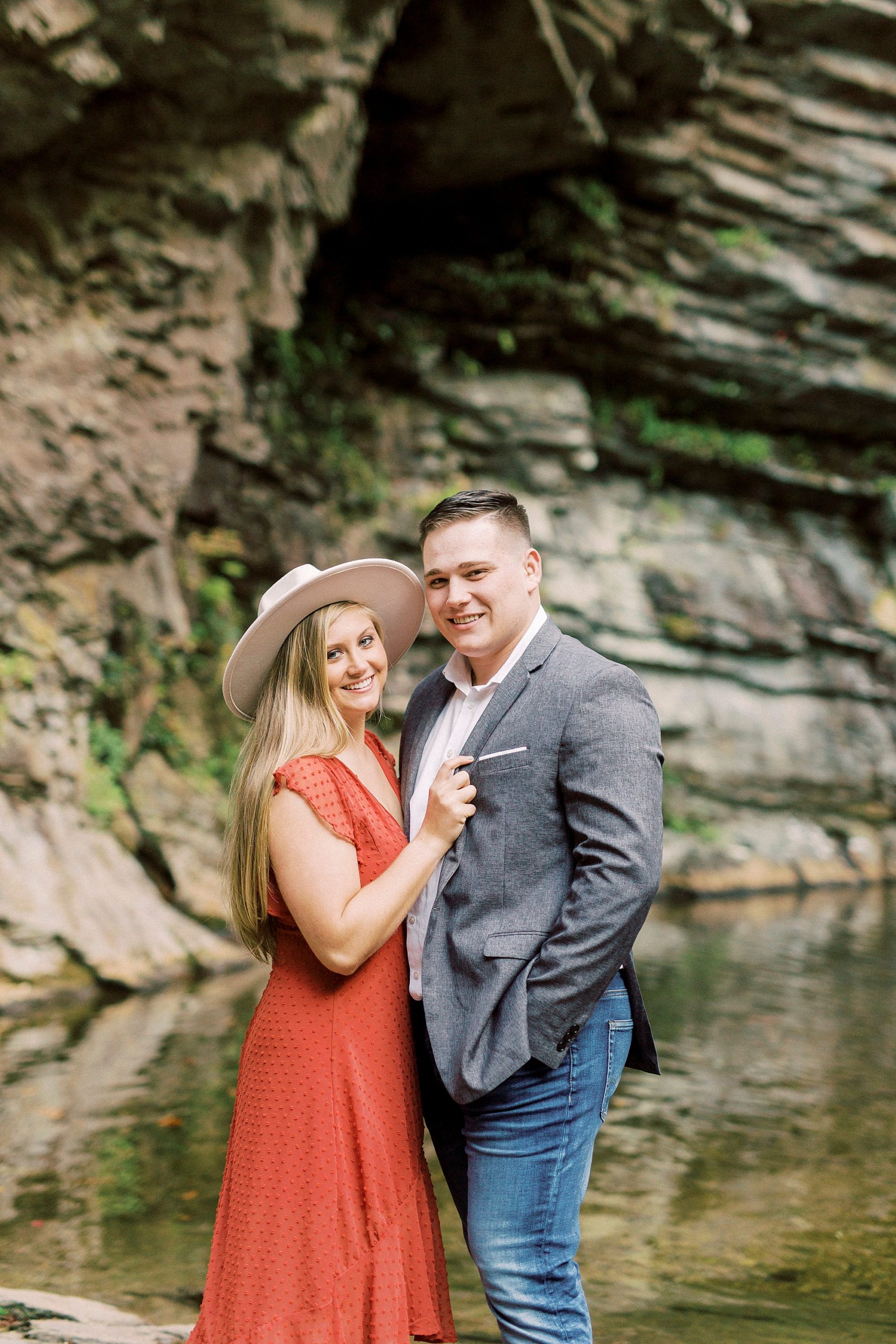bride poses in wide brimmed hat hugging groom