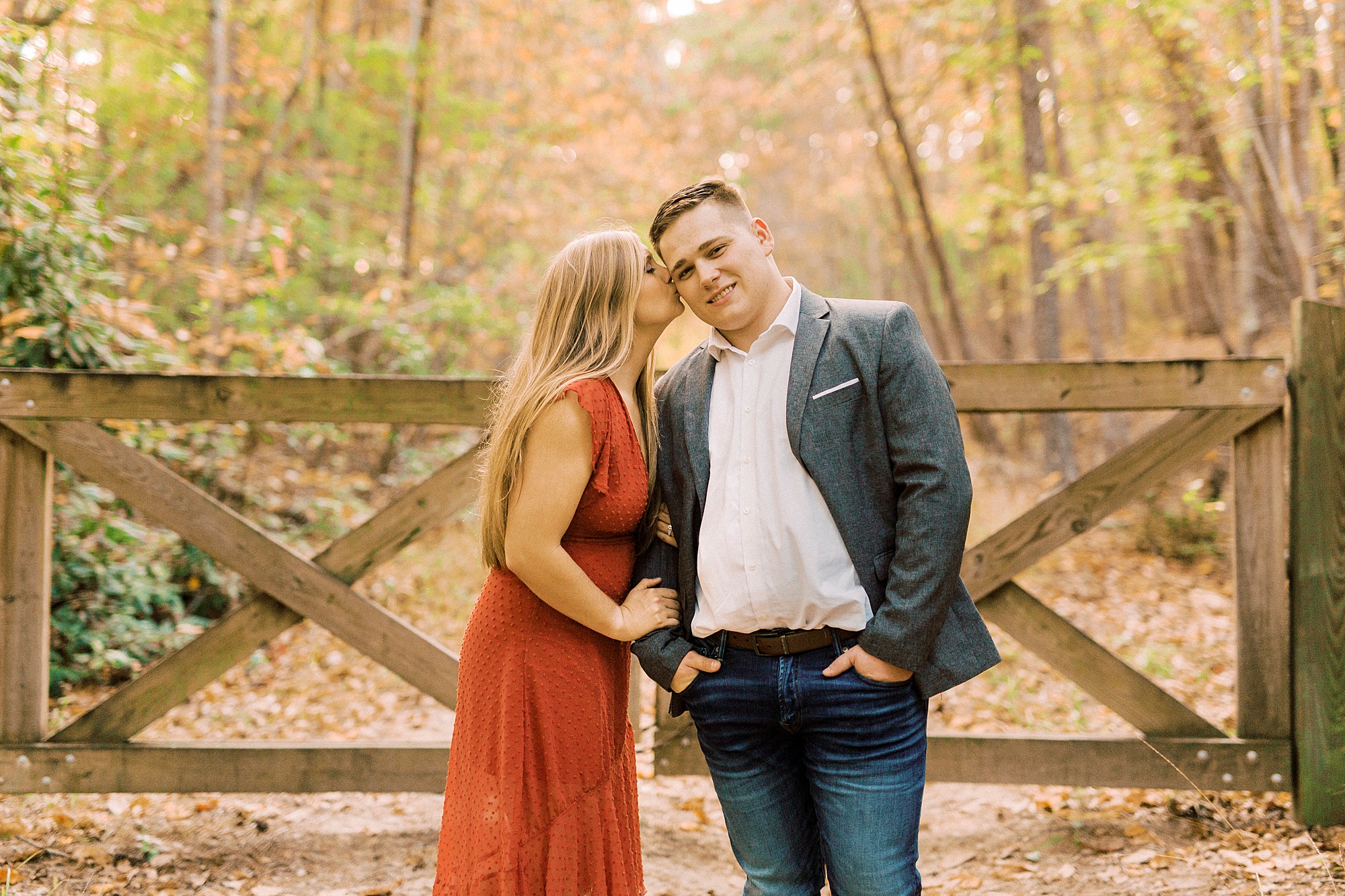 bride kisses groom's cheek during fall engagement photos