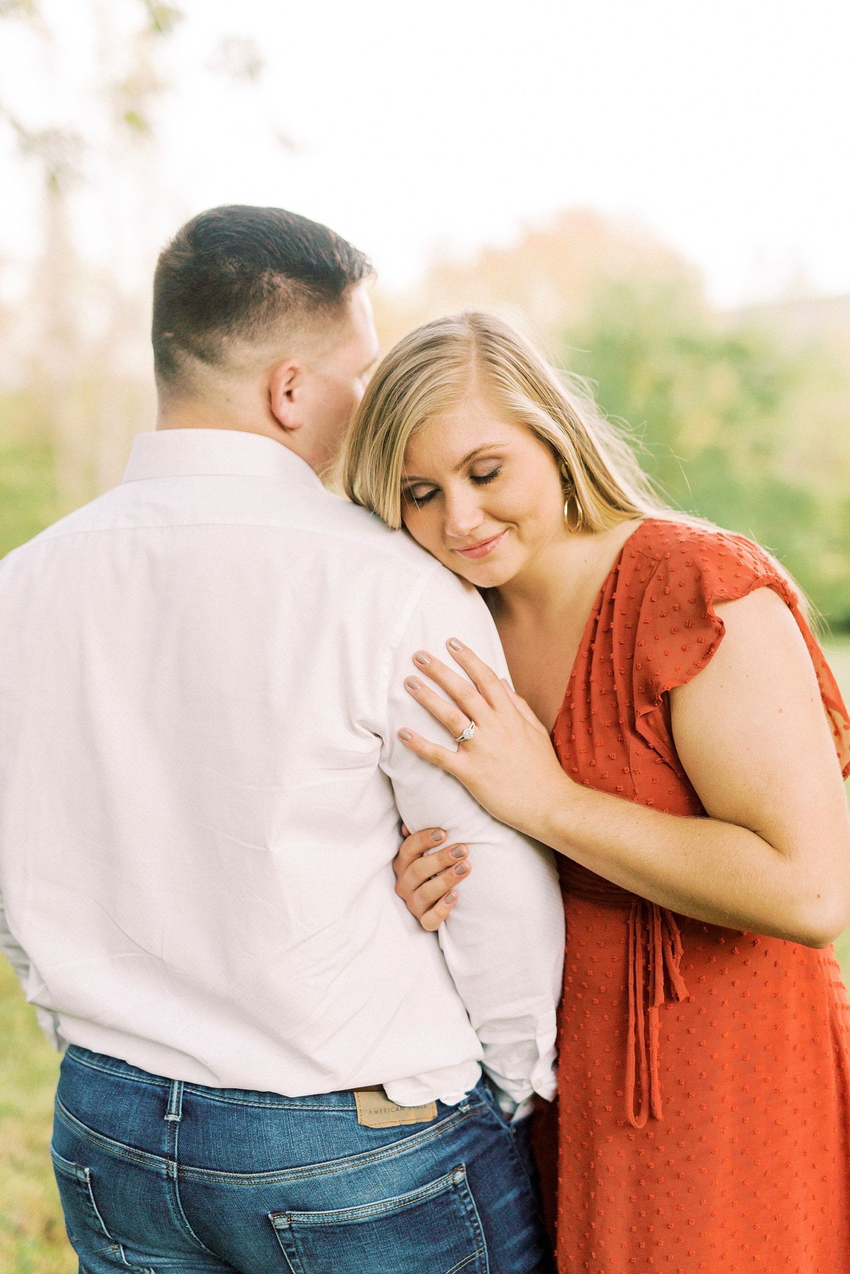 bride leans on groom's arm showing off engagement ring