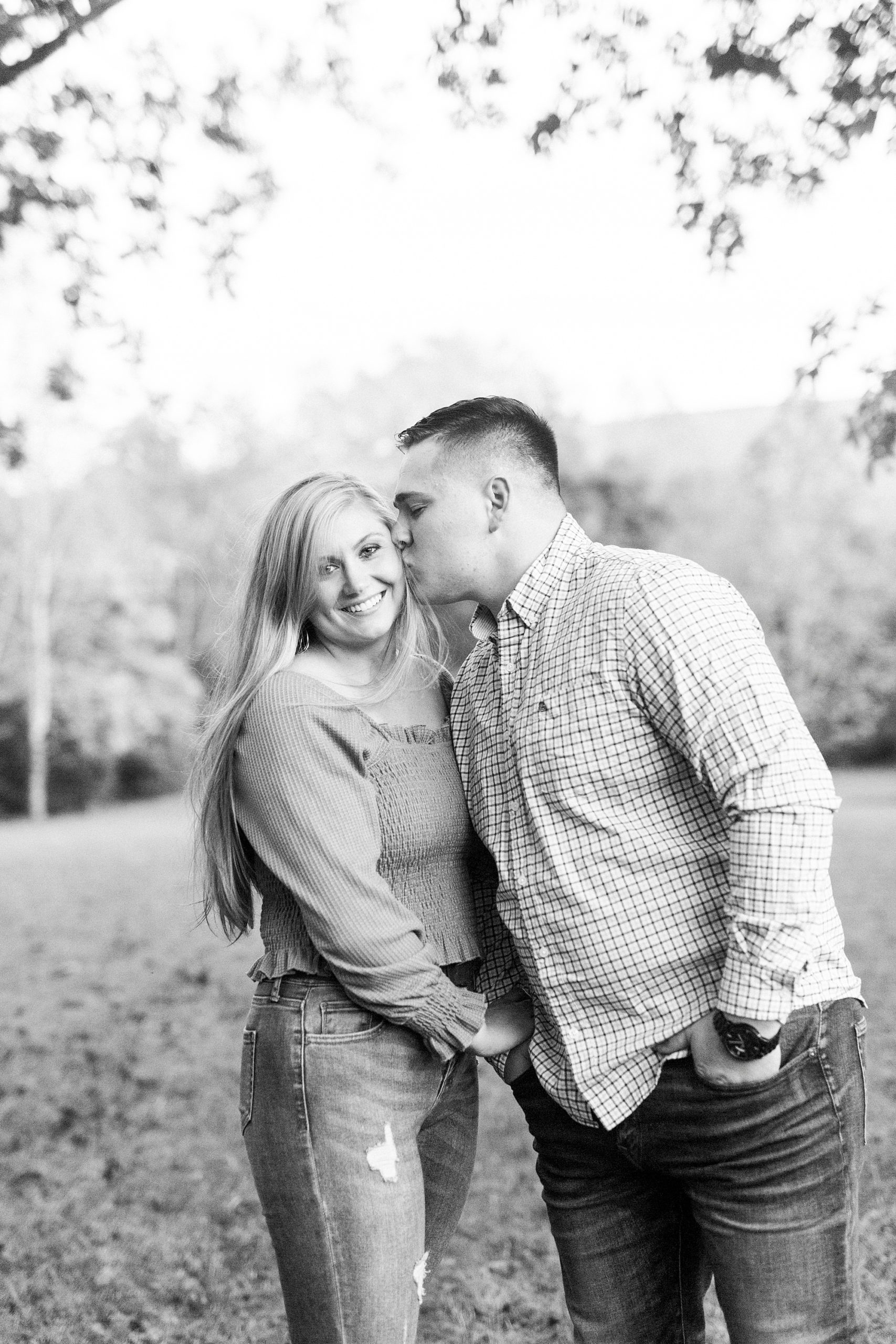 groom leans to kiss bride's cheek during fall photos