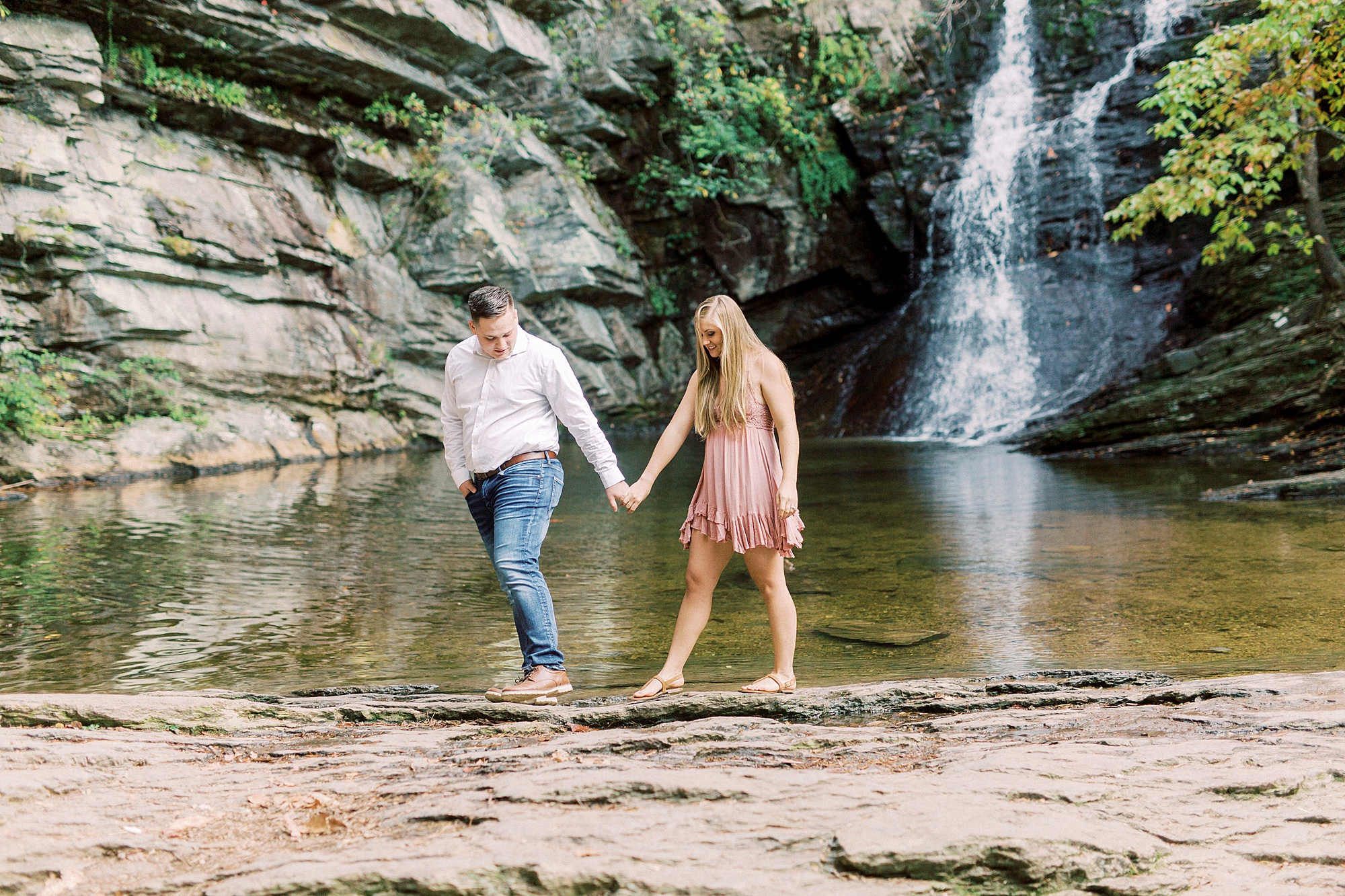 engaged couple walks through waterfall at Hanging Rock State Park