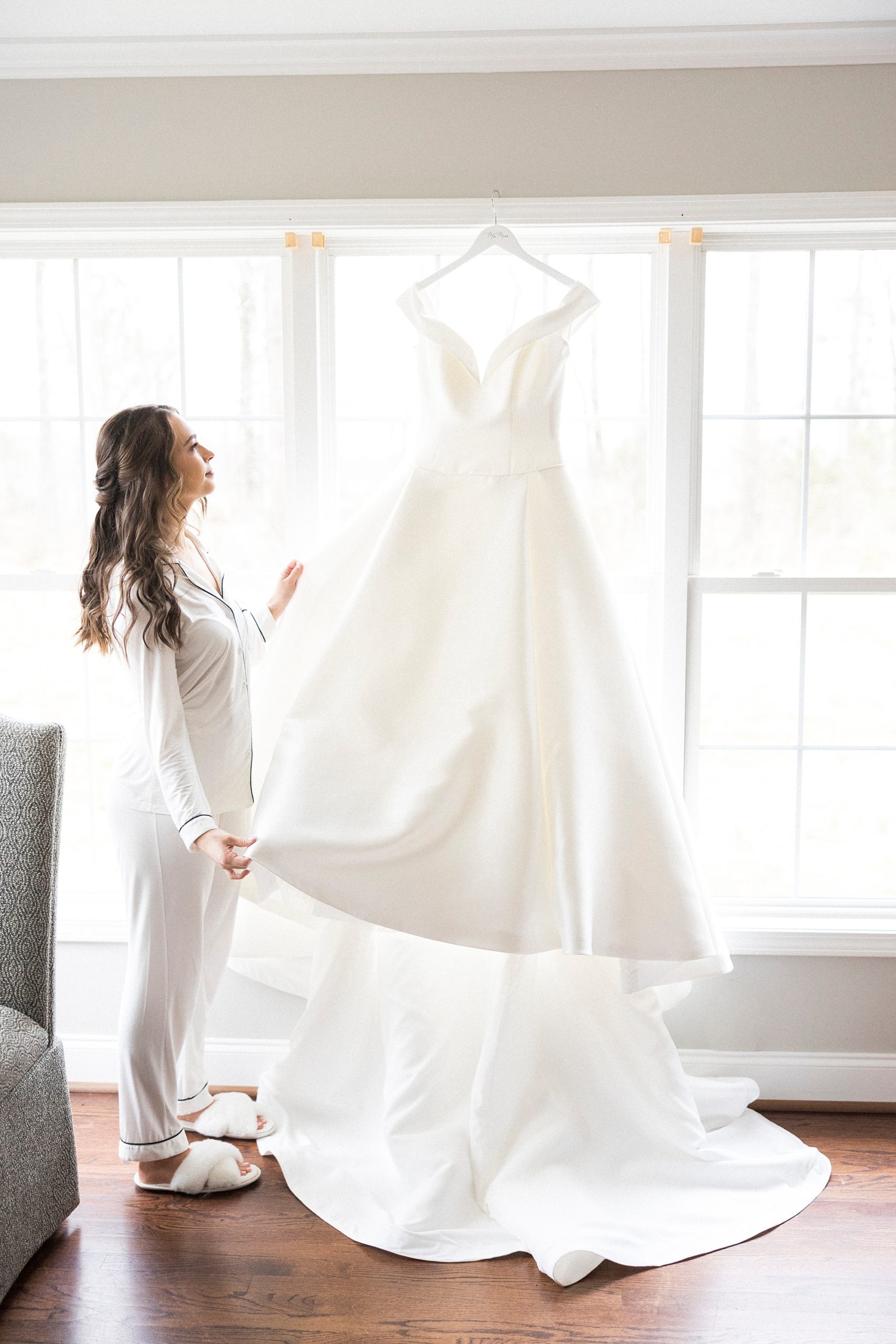 bride looks up at wedding gown hanging at The Farm at Brusharbor
