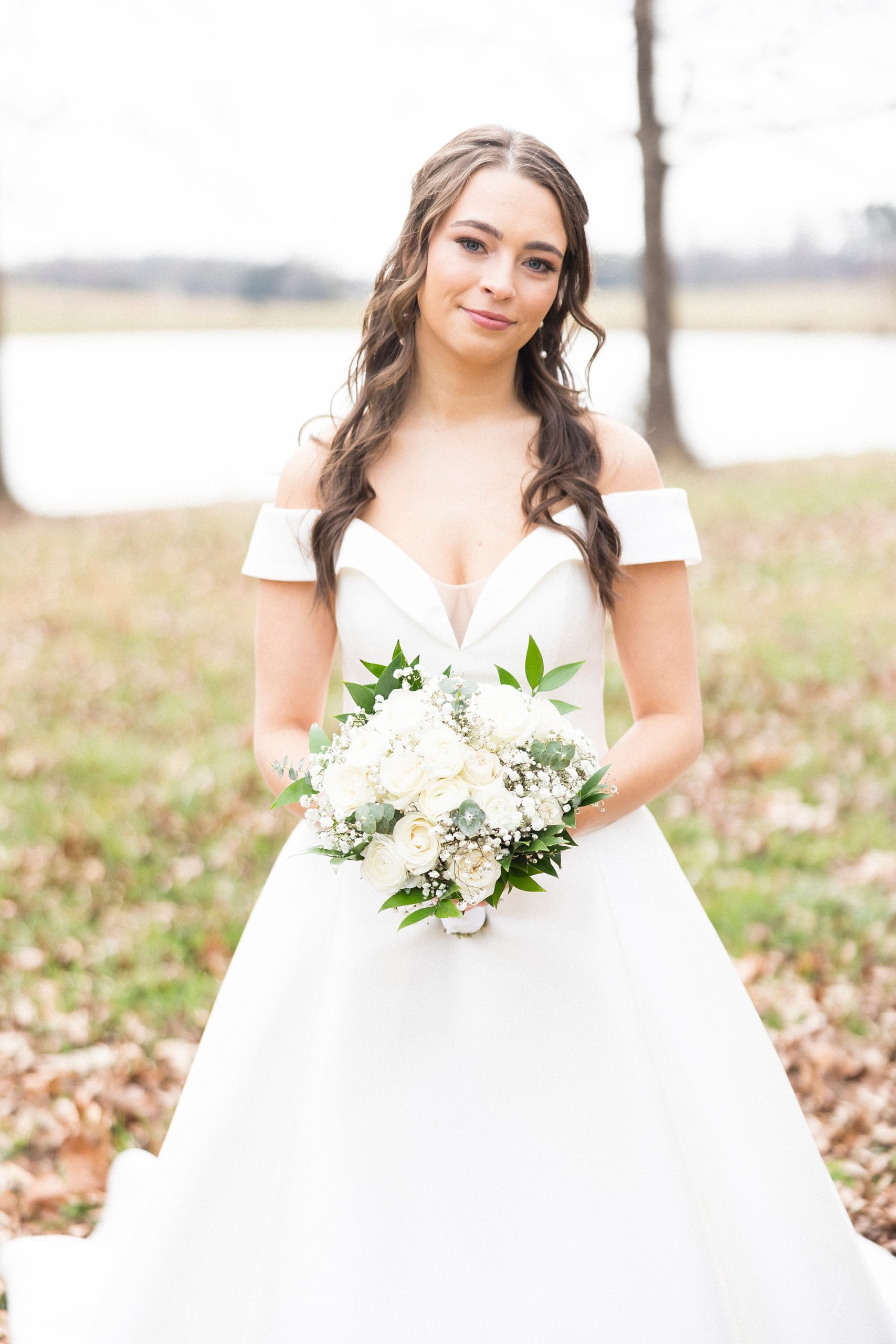 bride holds bouquet of white flowers in off-the-shoulder gown