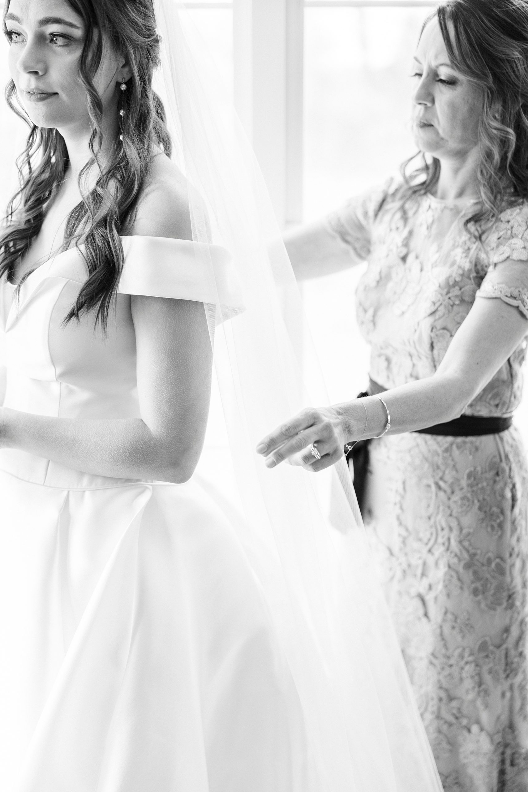 mother helps bride with veil on wedding day