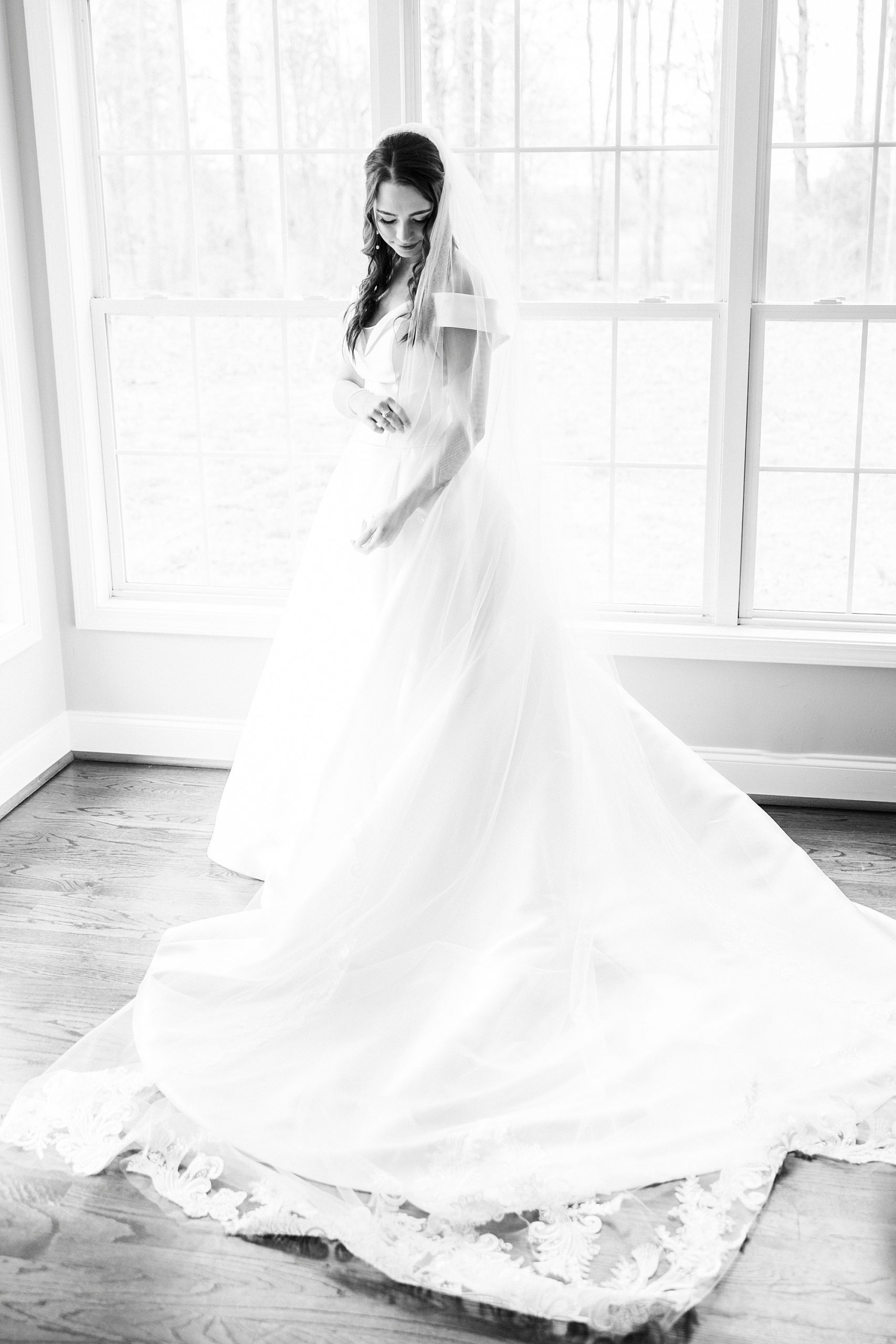 bride stands in wedding gown with veil wrapped around her