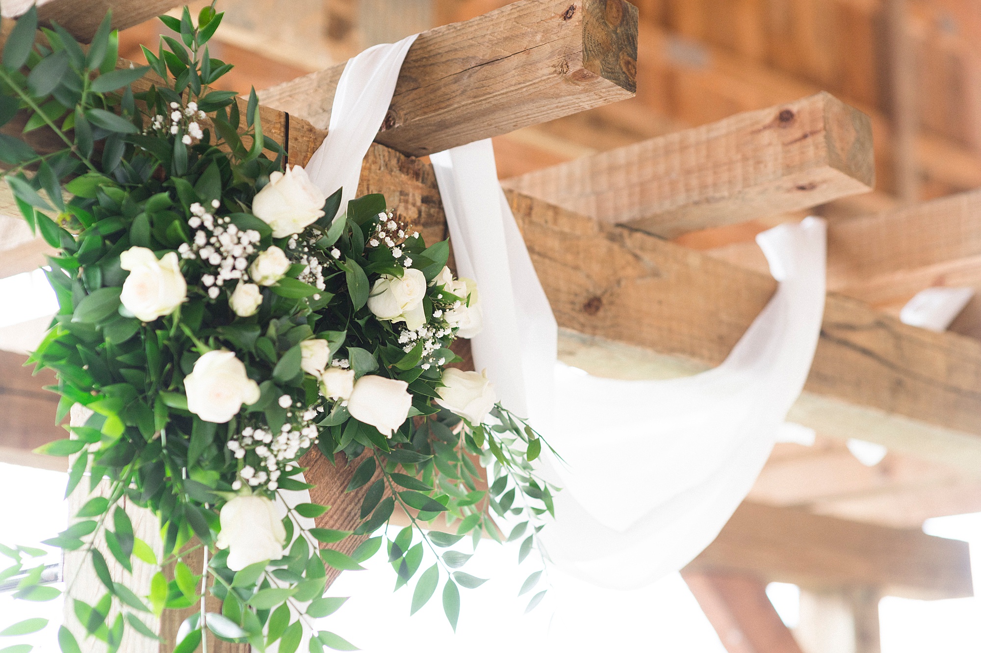 floral arrangement at top of wooden arbor for Christ-centered ceremony at The Farm at Brusharbor