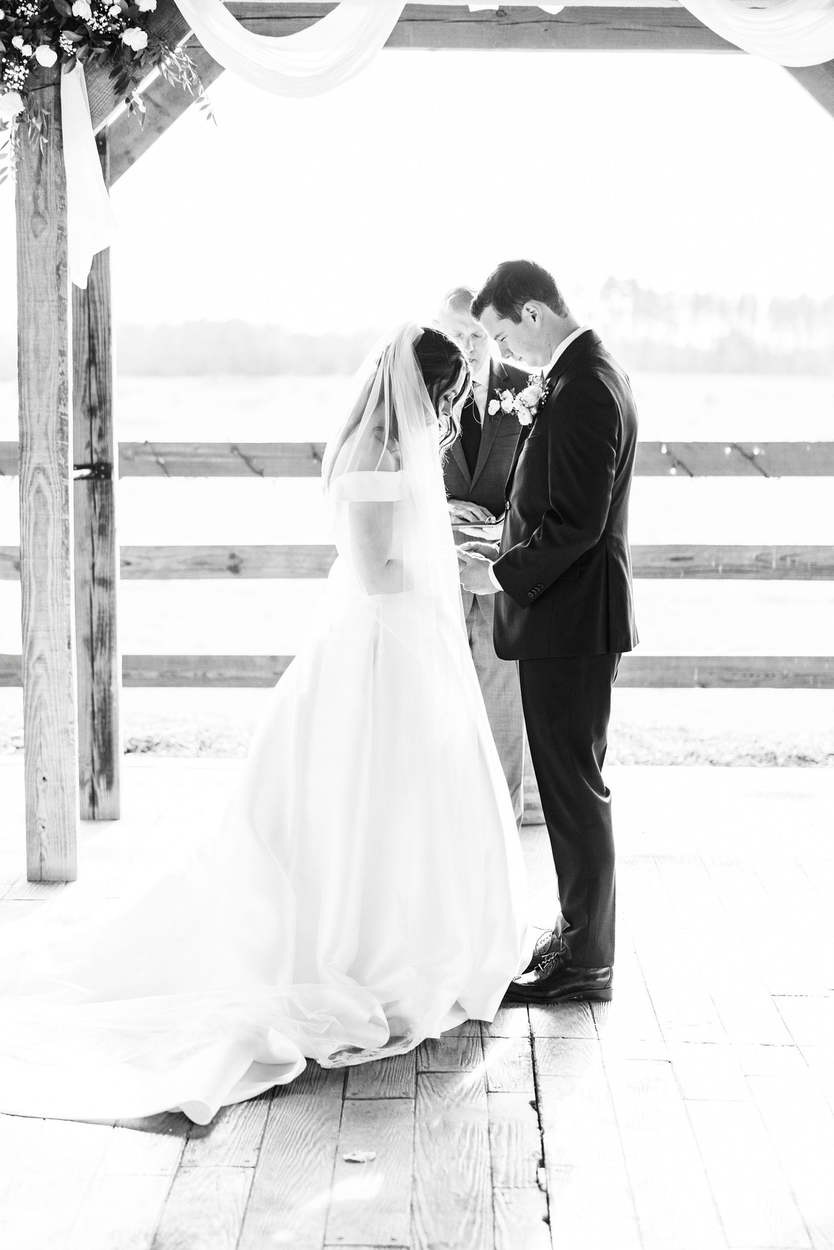 bride and groom bow heads during Christ-centered ceremony at The Farm at Brusharbor