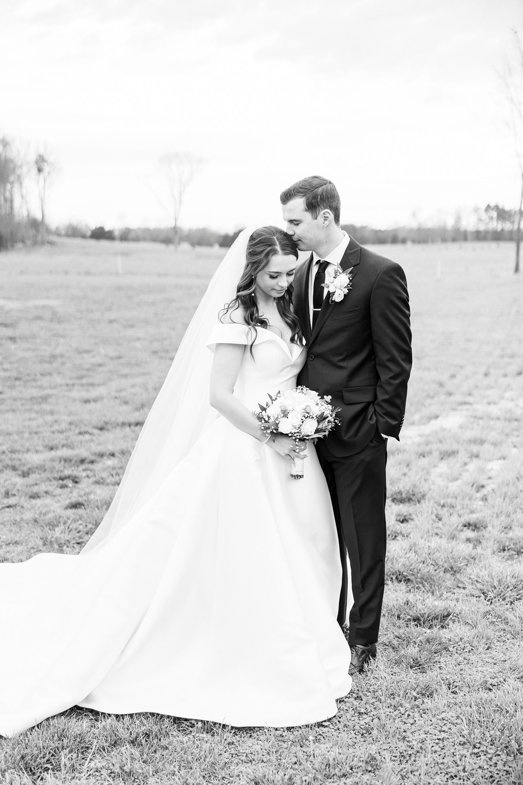 groom kisses top of bride's head during wedding portraits