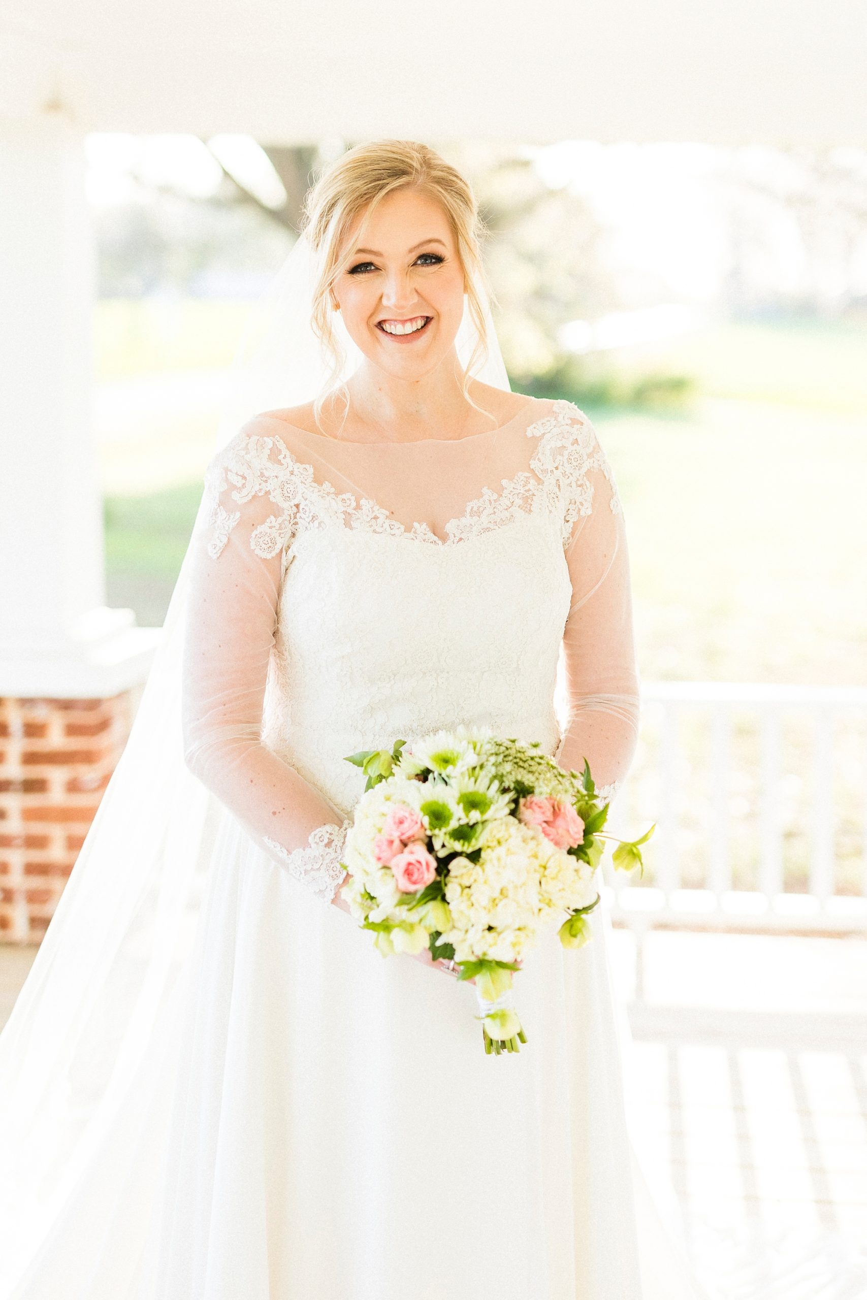 bride holds bouquet of white and pink flowers on front porch