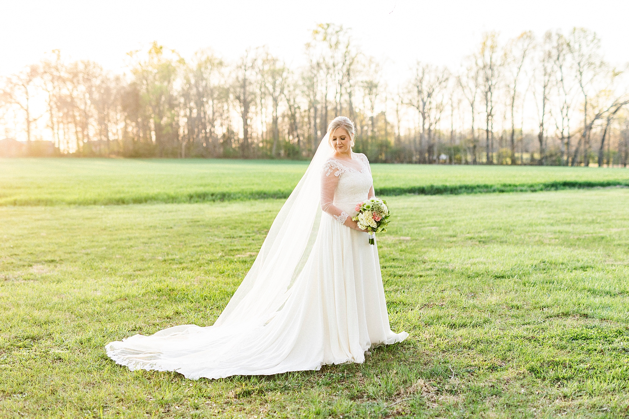 bride holds bouquet of white and pink flowers with veil draped behind her