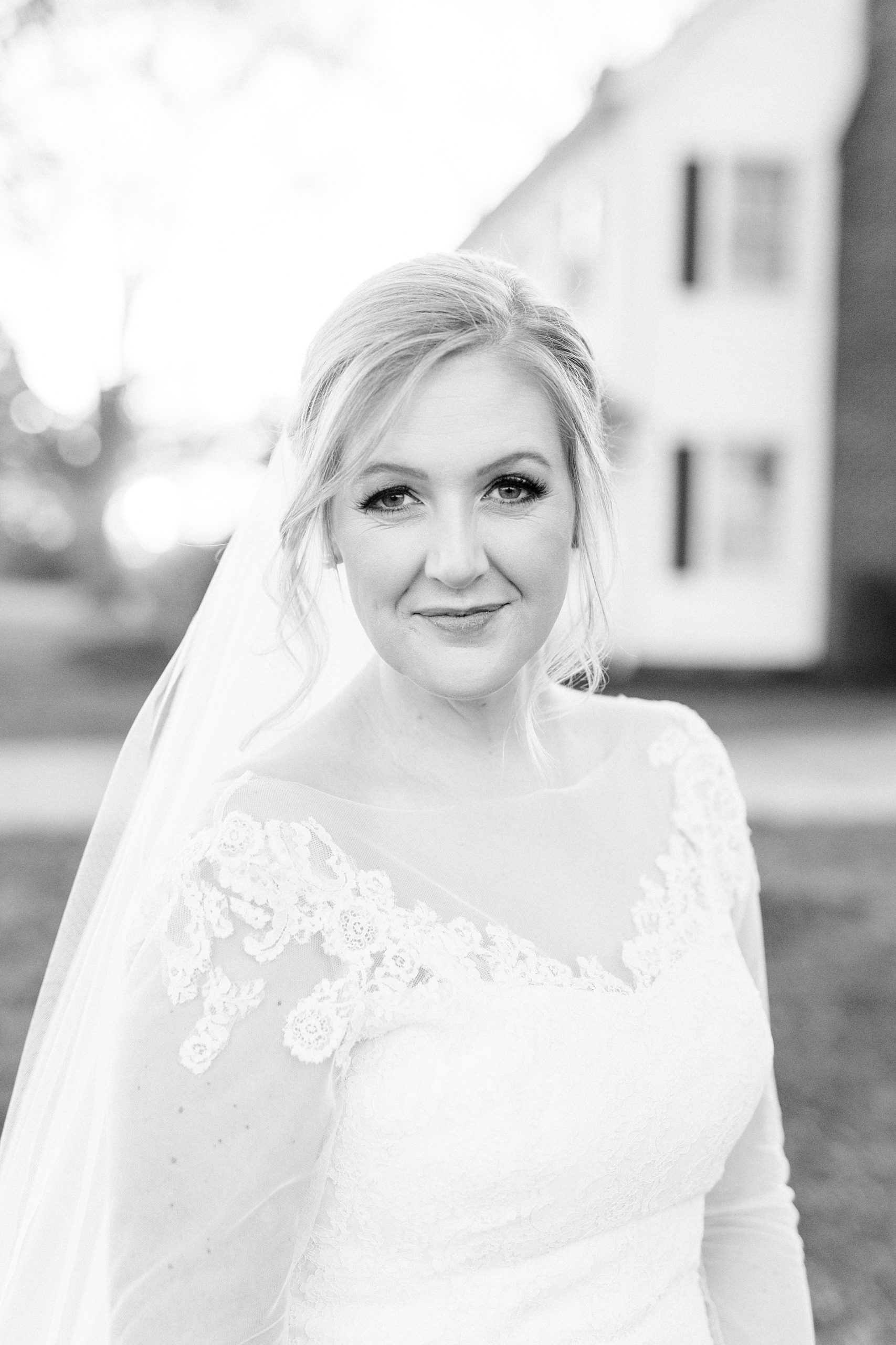 bride smiles next to farmhouse during Mooresville bridal portraits
