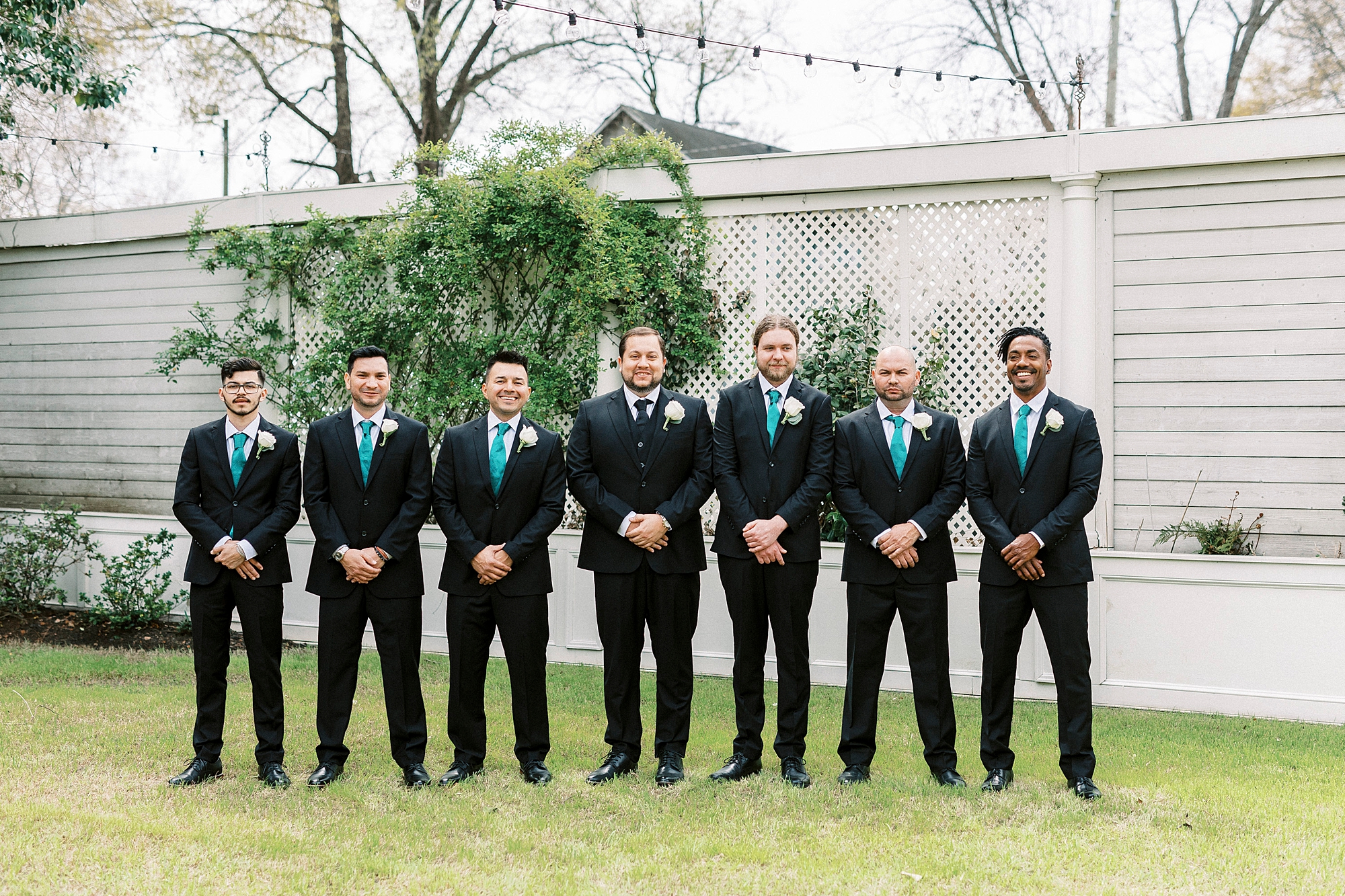 groomsmen stand in row with green ties