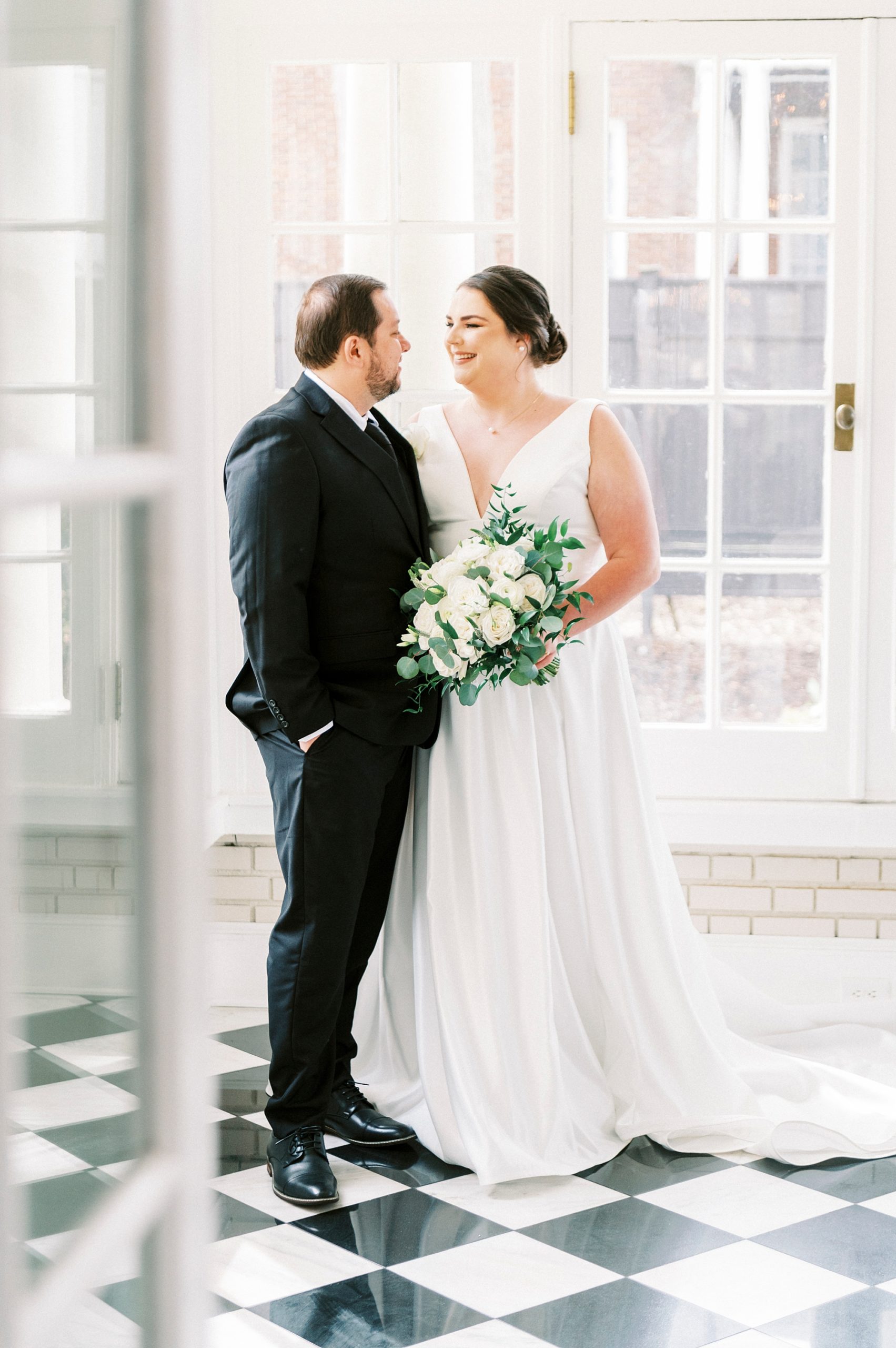 newlyweds pose in corner of room with black and white floors at Separk Mansion