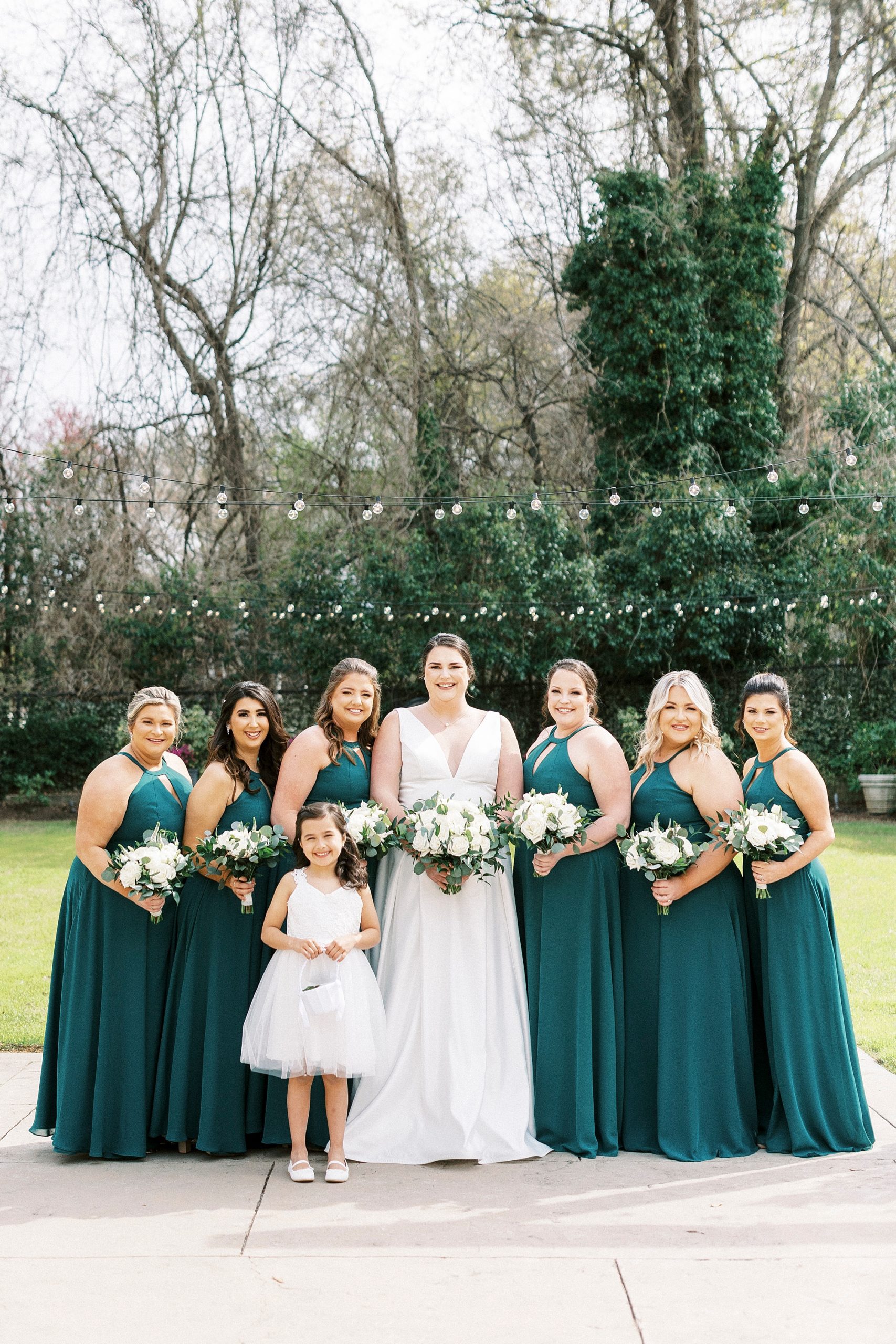 bride and bridesmaids in emerald green gowns pose in gardens at Separk Mansion