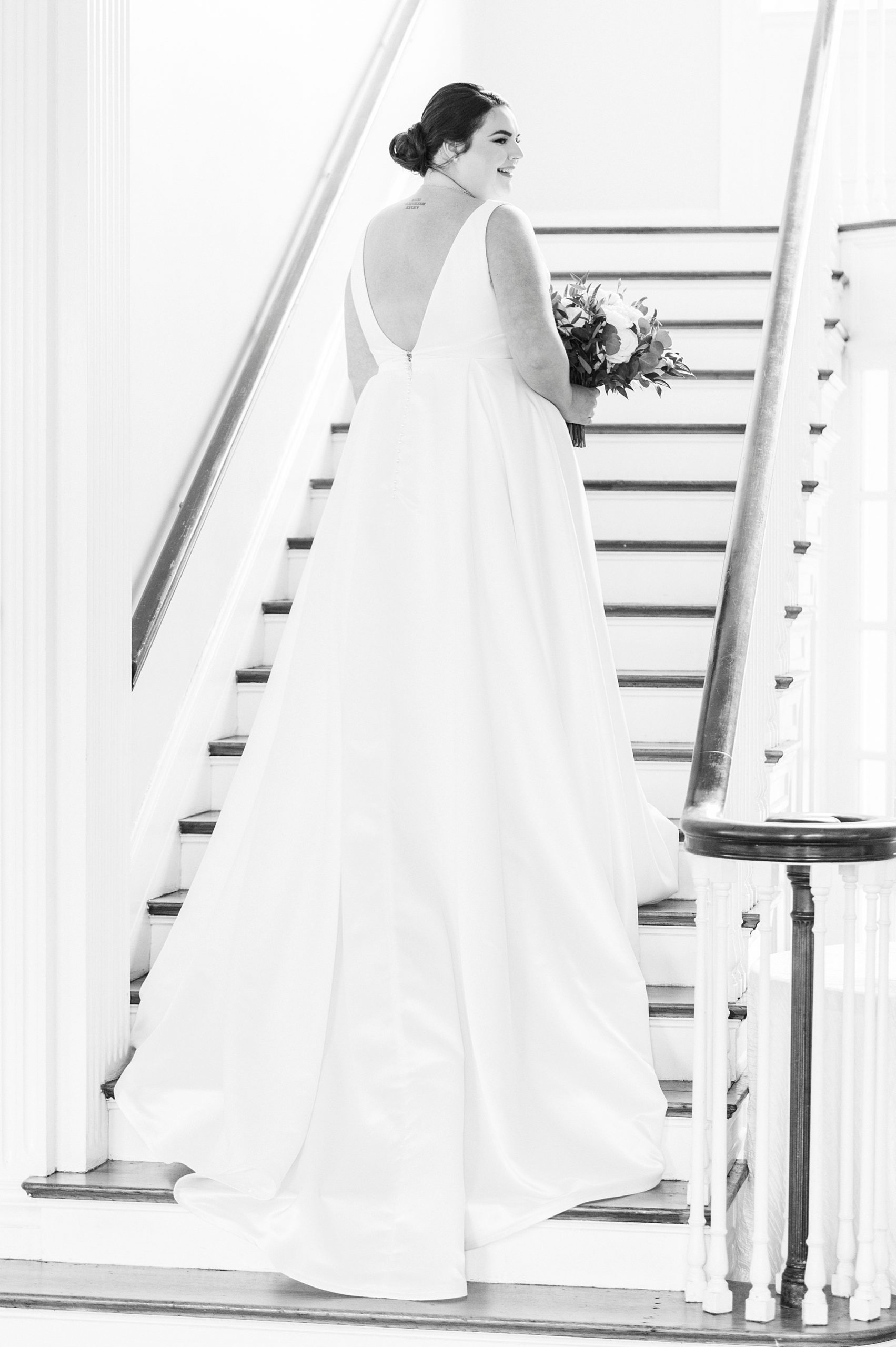 bride stands on steps at Separk Mansion with wedding dress trailing behind her