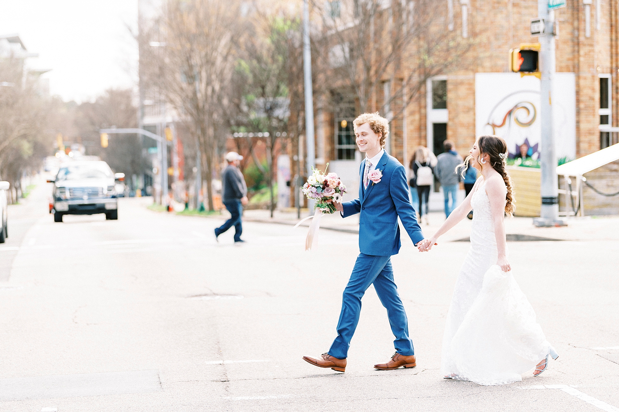 bride and groom hold hands walking through downtown Raleigh