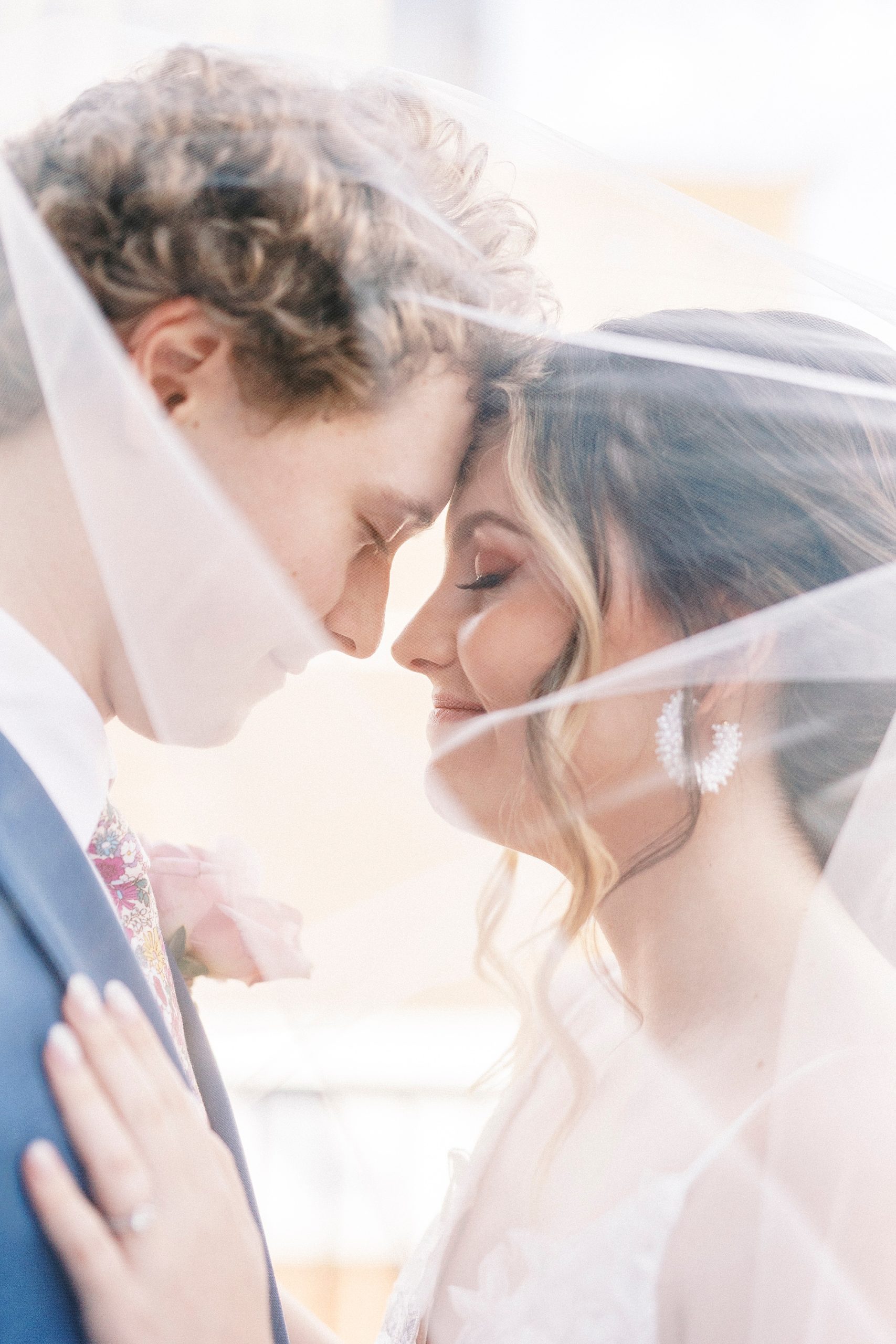 newlyweds hug under bride's veil