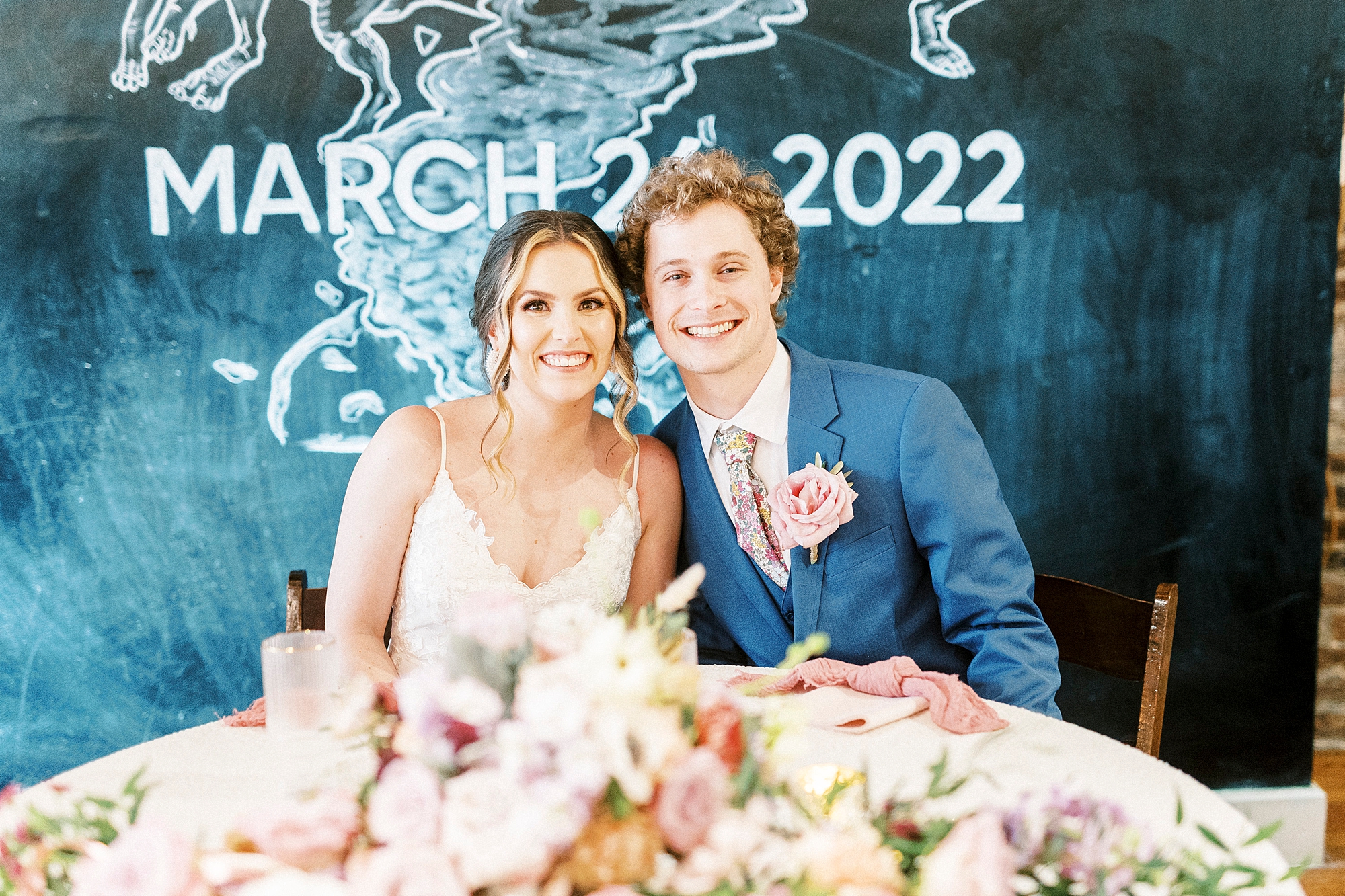 bride and groom sit by chalkboard at the Stockroom at 230